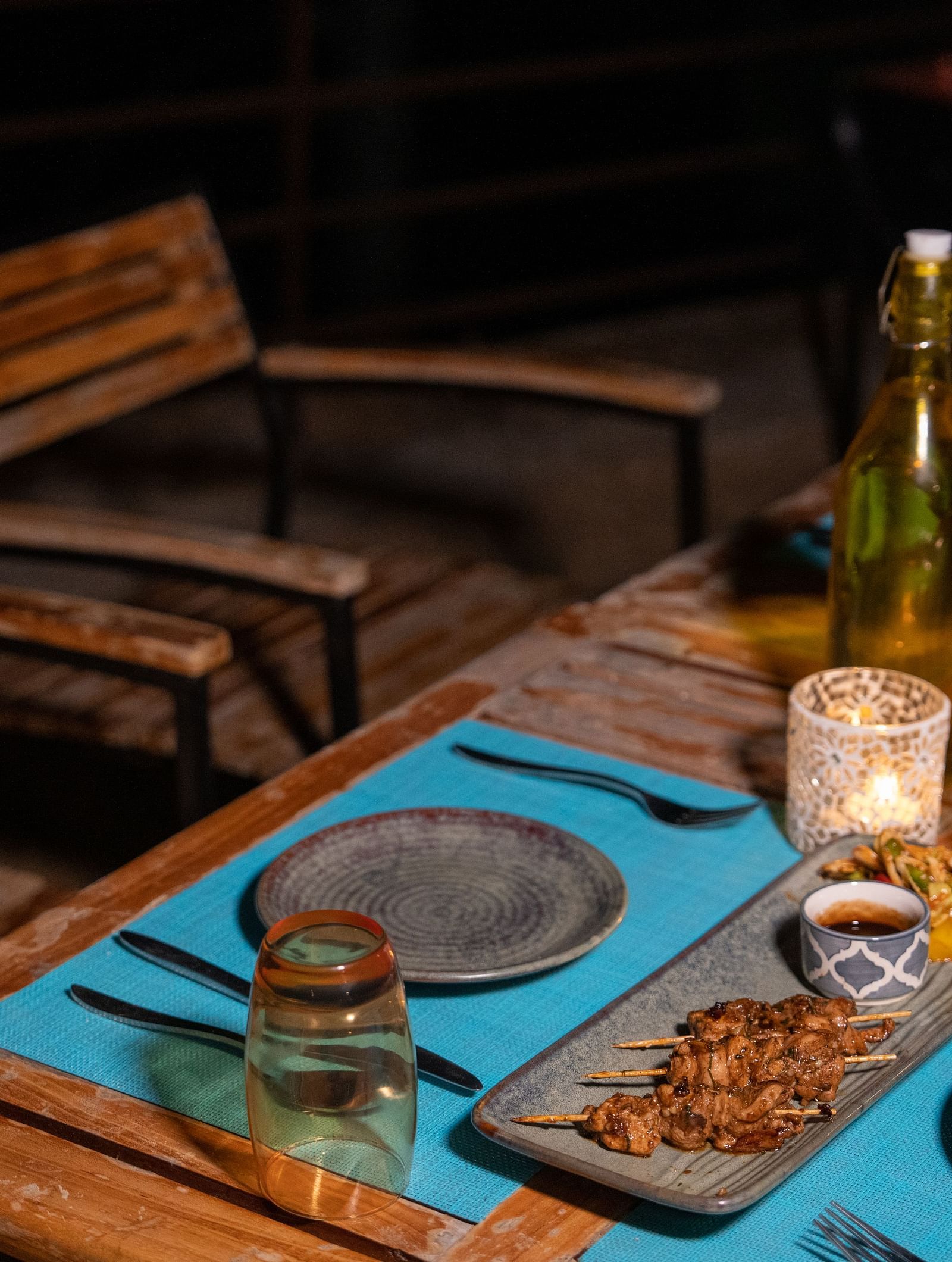 An outdoor dining area in the evening with a table set with food, drinks, and cutlery at BluSalzz Escapade Resort, Lansdowne