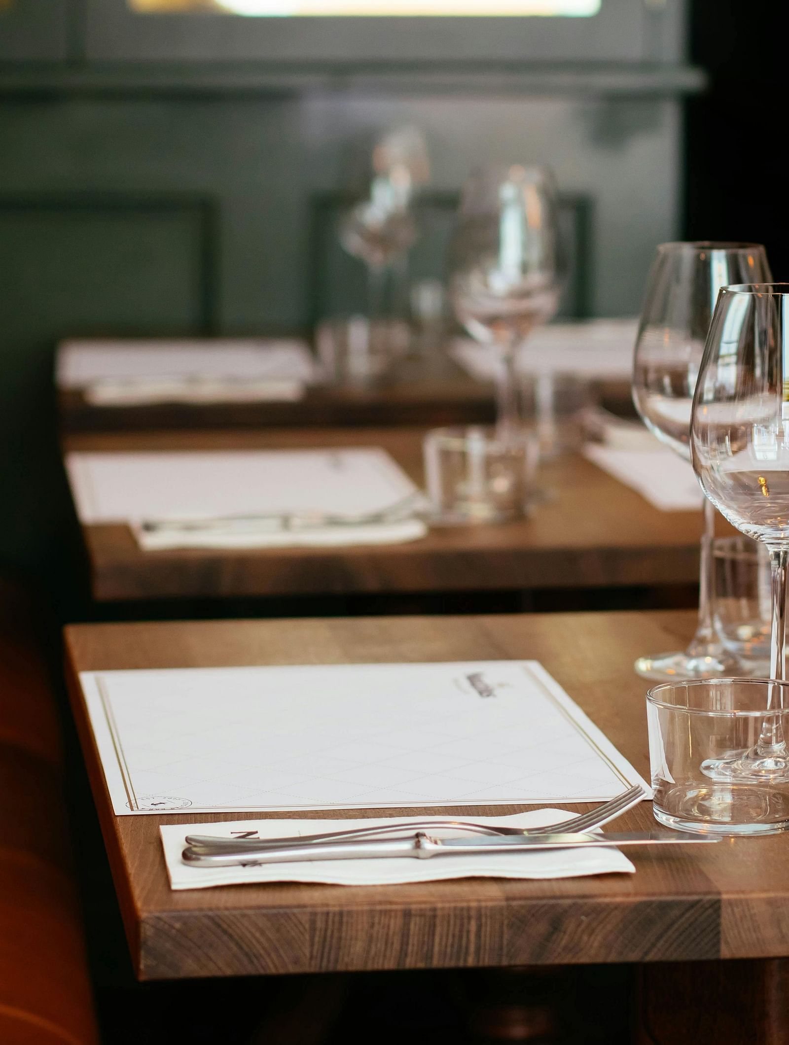 A dining setup with clear glasses placed near the menus on a wooden table.