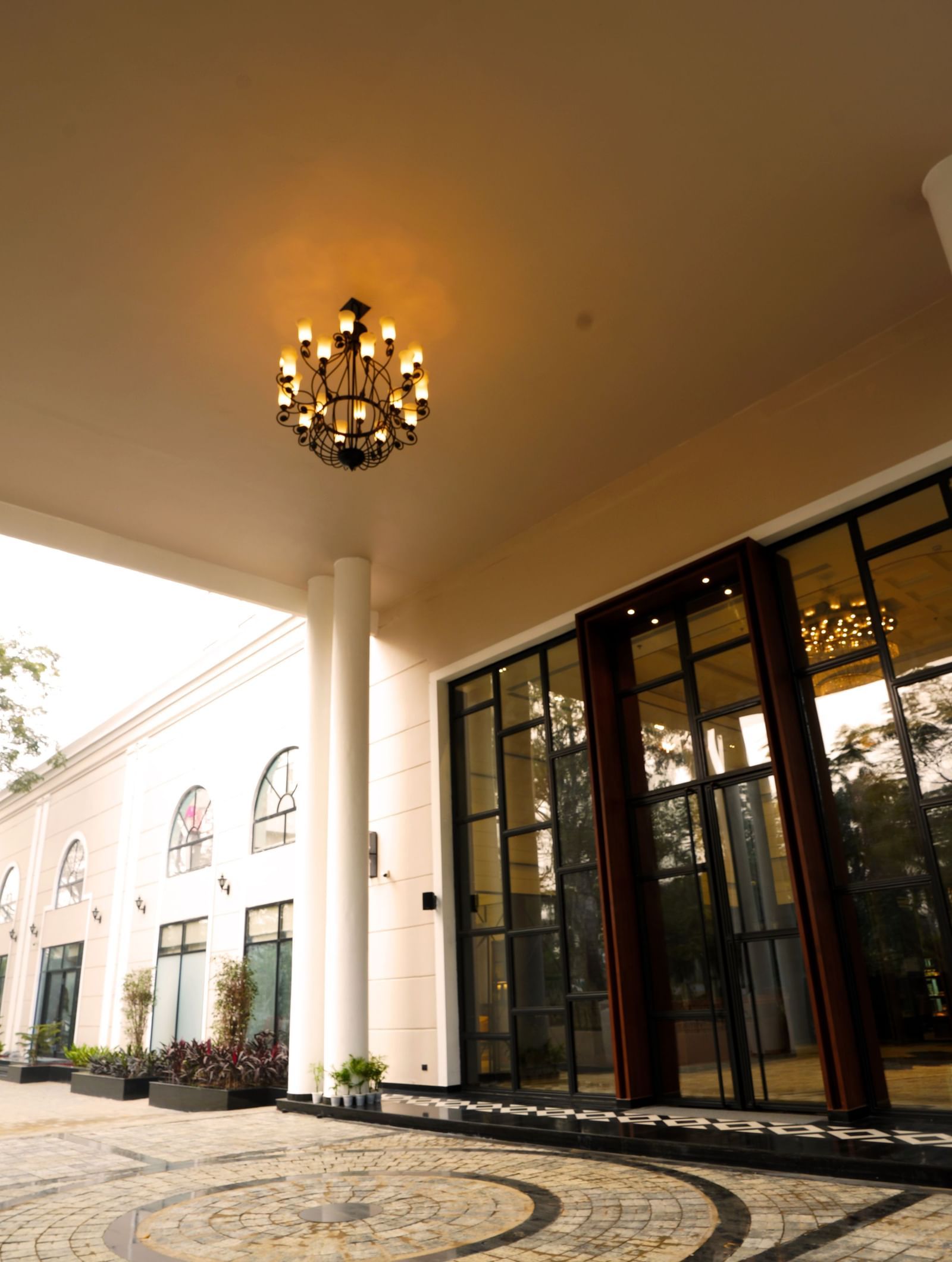 The entrance of Polo Hotel Agartala fetauring a chandelier and a giant floor to glass door.