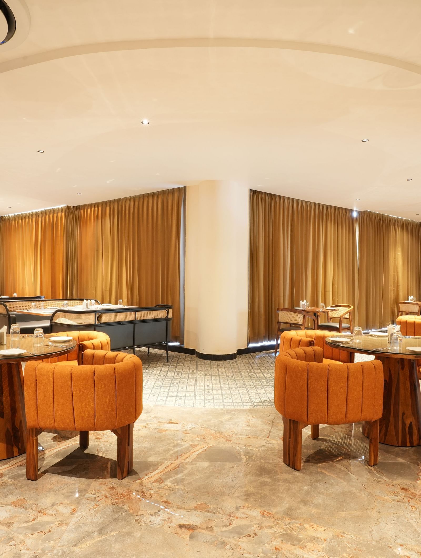 Fine Dine with multiple tables and orange chairs at The Qualia Resort Club & Brewery, Udaipur.