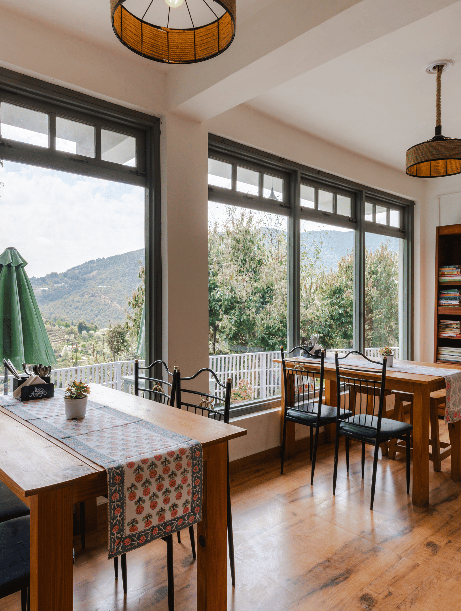 A dining area with tables and chairs next to a large window overlooking a patio at Ziran Retreat.