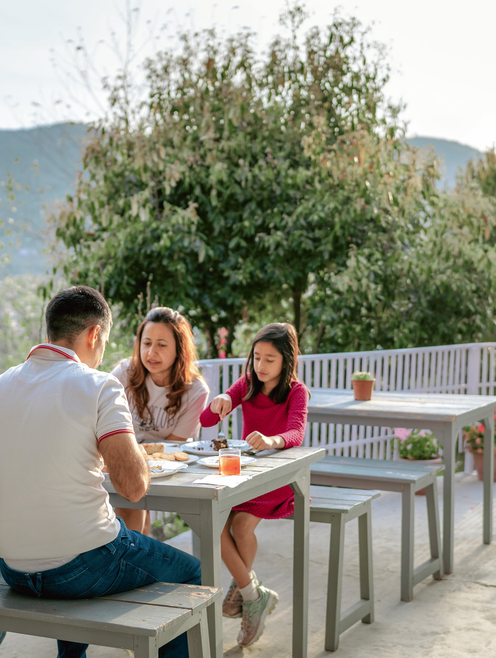 A shot of four people sitting at a picnic table on the outdoor terrace of Ziran Retreat, talking and laughing.