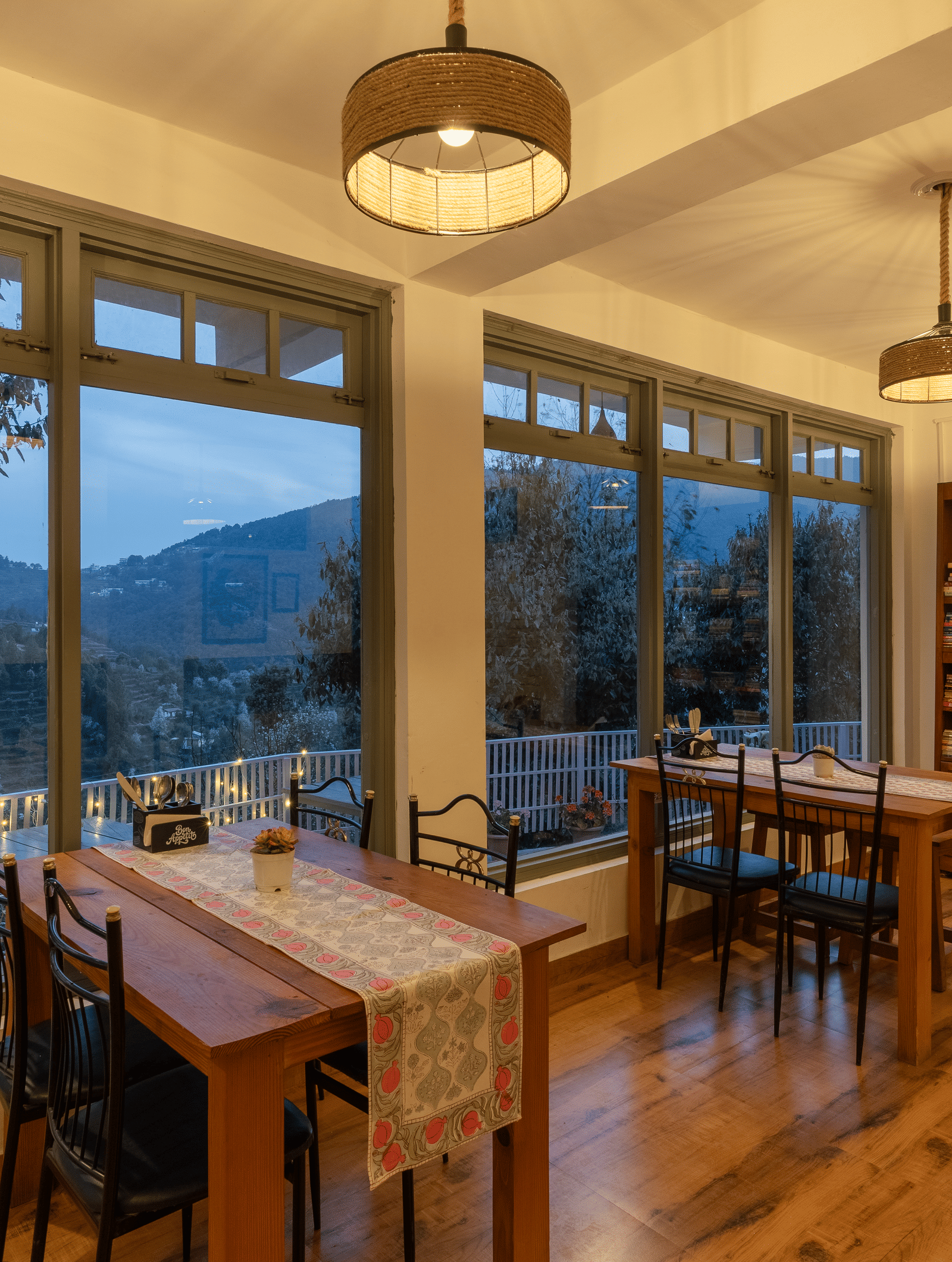 An indoor dining area with wooden tables and large windows at Ziran Retreat.