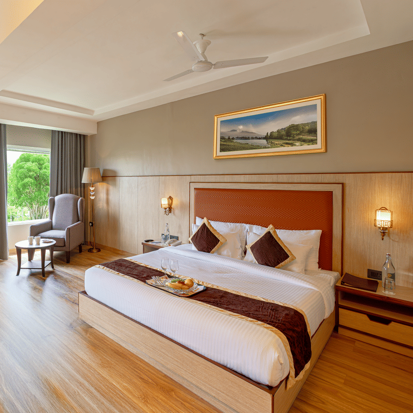 Elegant room at The Lalita Grand Mathura - Vrindavan with a king size bed, wooden flooring, large window views, and refined contemporary decor.