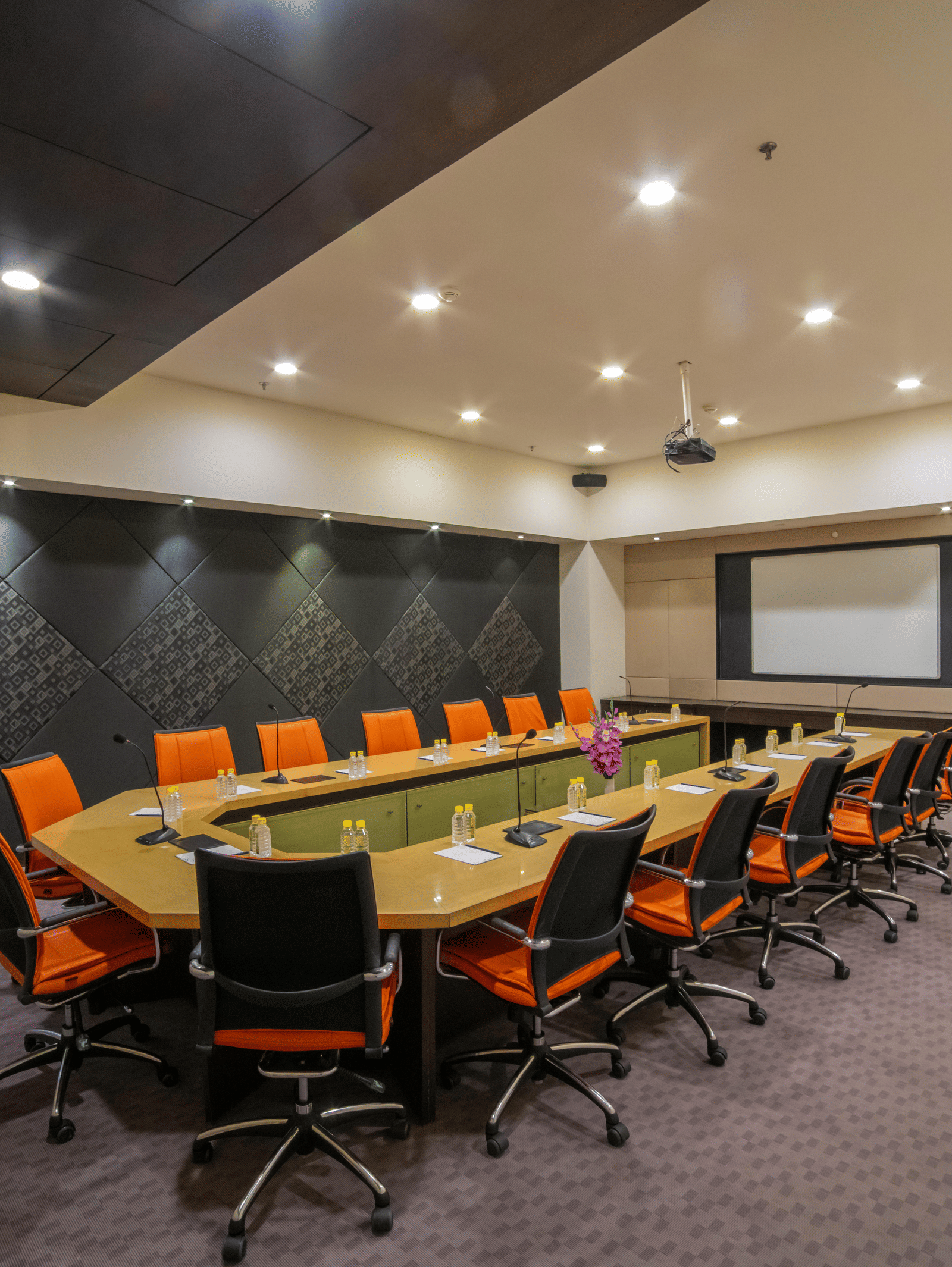 Conference room with a long table, orange chairs, and presentation screen at Narayani Heights Hotel & Resorts, Ahmedabad.