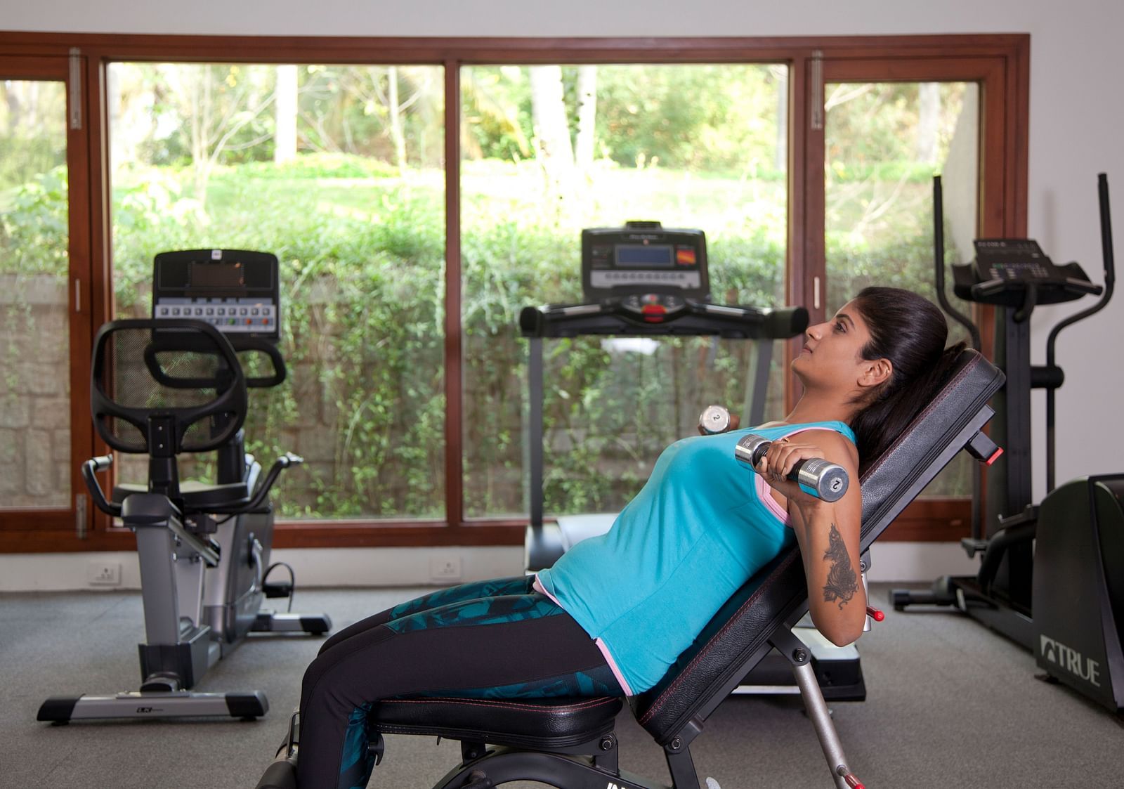 Person using exercise equipment in a room with large windows, fitness setting - Shreyas Retreat
