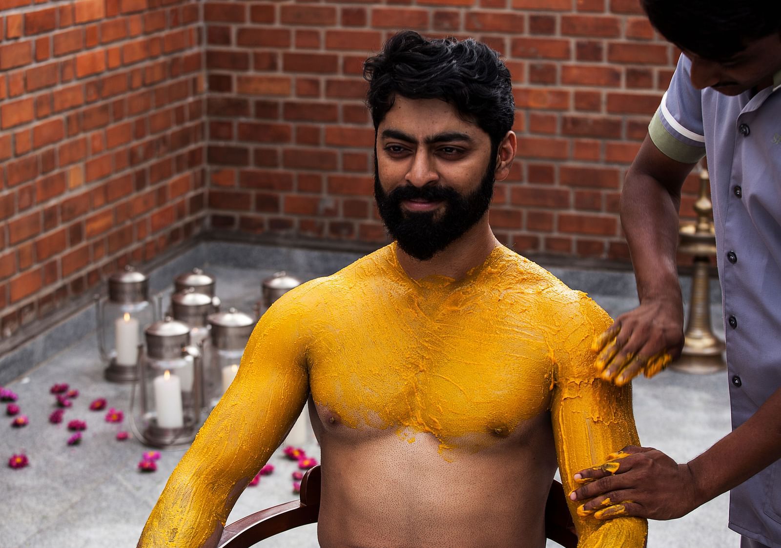 A person with yellow markings on their body, brick wall background - Shreyas Retreat