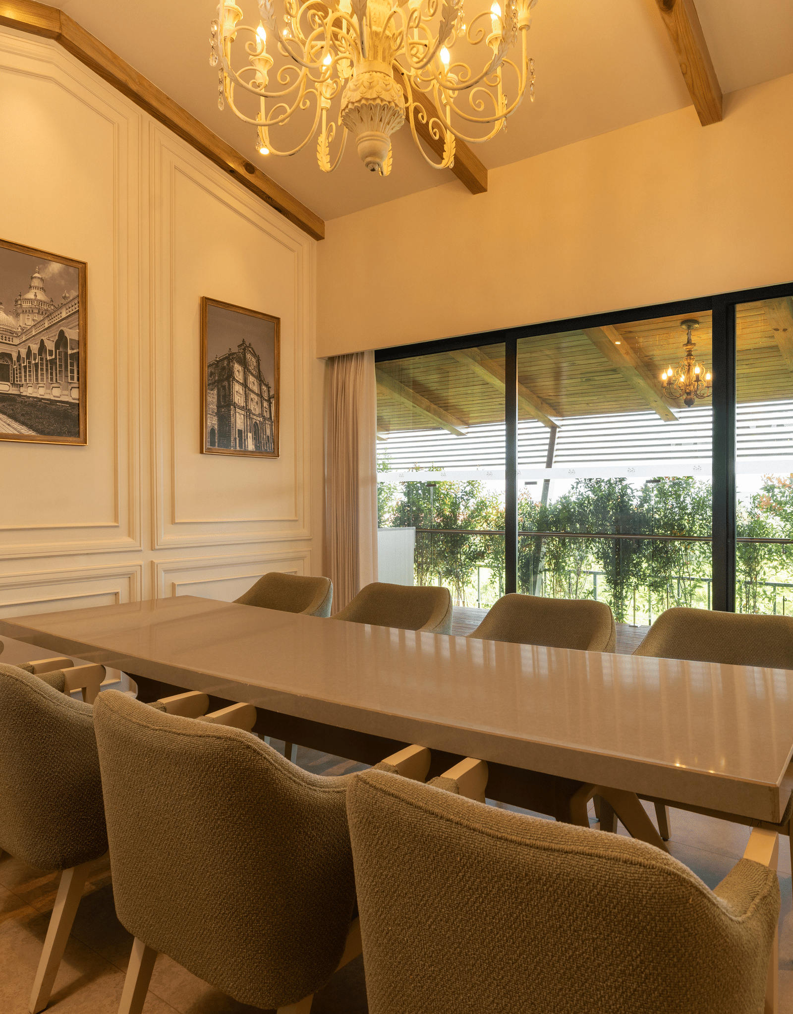 A brightly-lit boardroom at The Evren, Vagator, featuring a long conference table with a window behind it overlooking the lush green lawns.