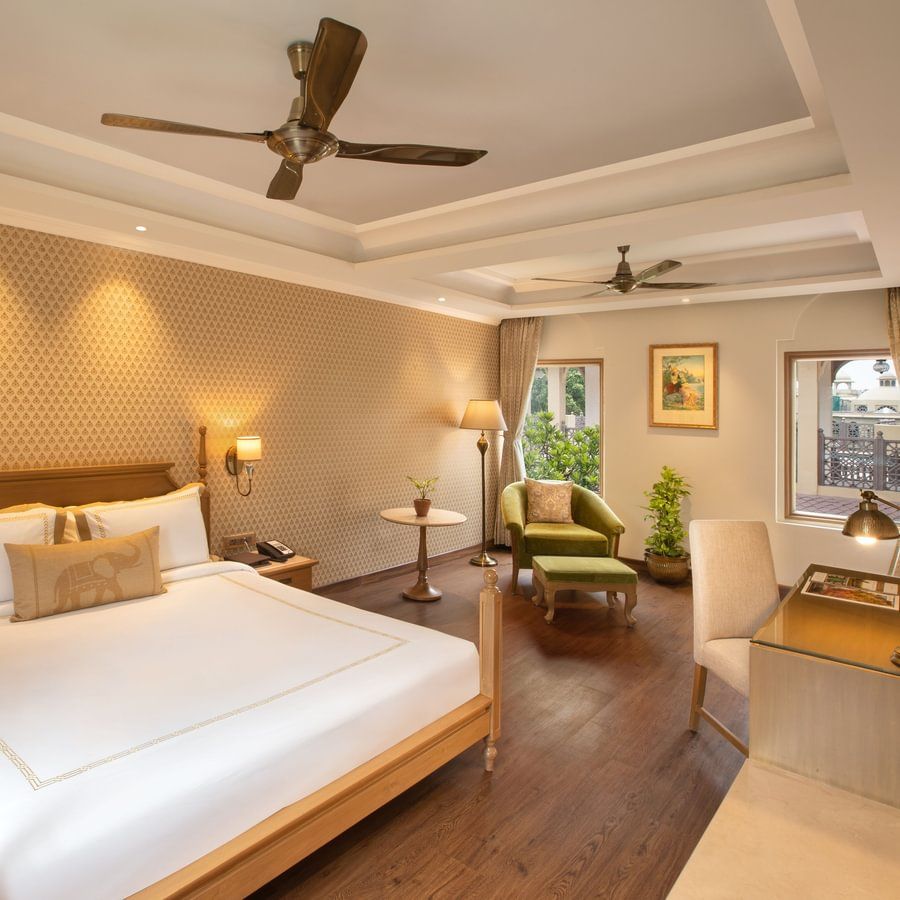Bedroom at Heritage Village Resorts & Spa, Manesar featuring double bed, ceiling fan, and warm-toned lighting.