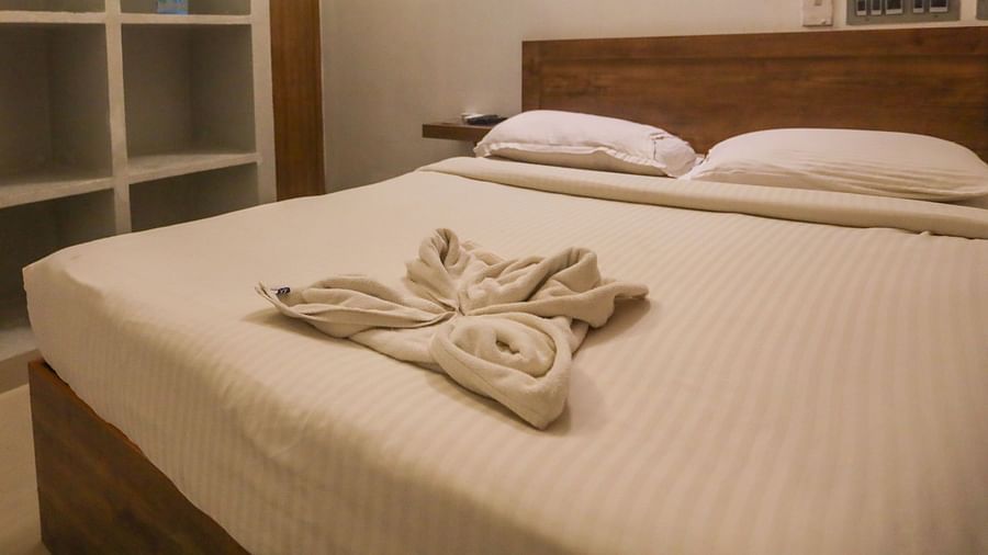 A corner view of a double bed room with plushy bed and shelves and a wall painting hanging at La  Paradise Residency  
