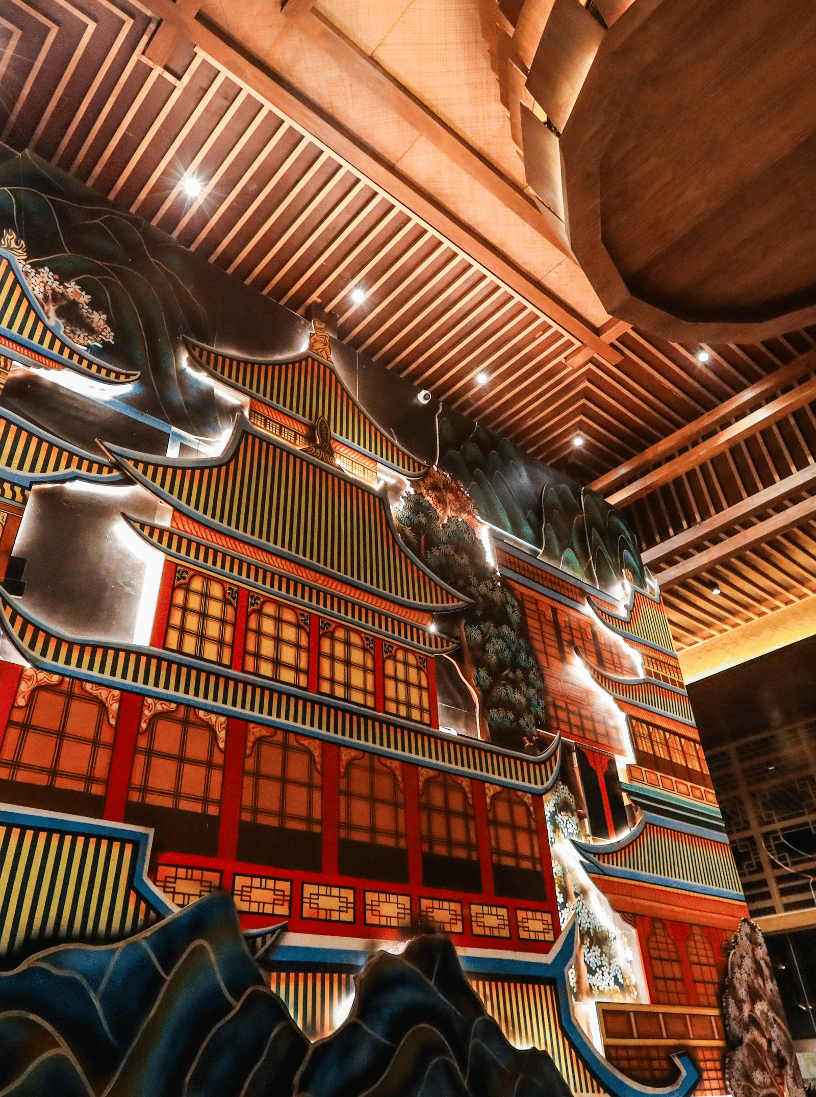 A dramatic, low-angle view of the large, colourful, three-dimensional pagoda mural on the wall at Ananta Spa & Resort, Jaipur.