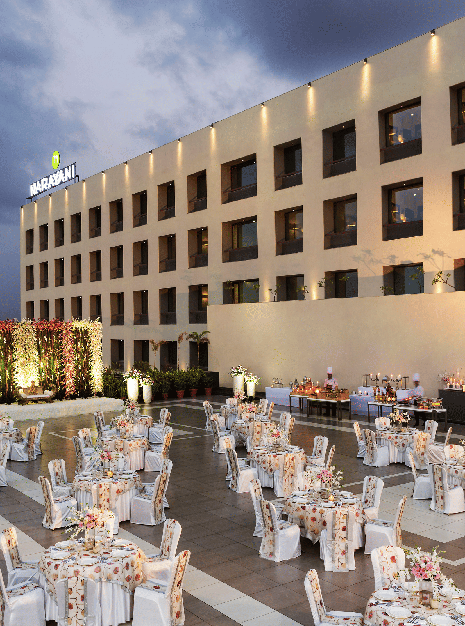 Outdoor banquet setup with white chairs and tables at Narayani Heights Hotel & Resorts, Ahmedabad.
