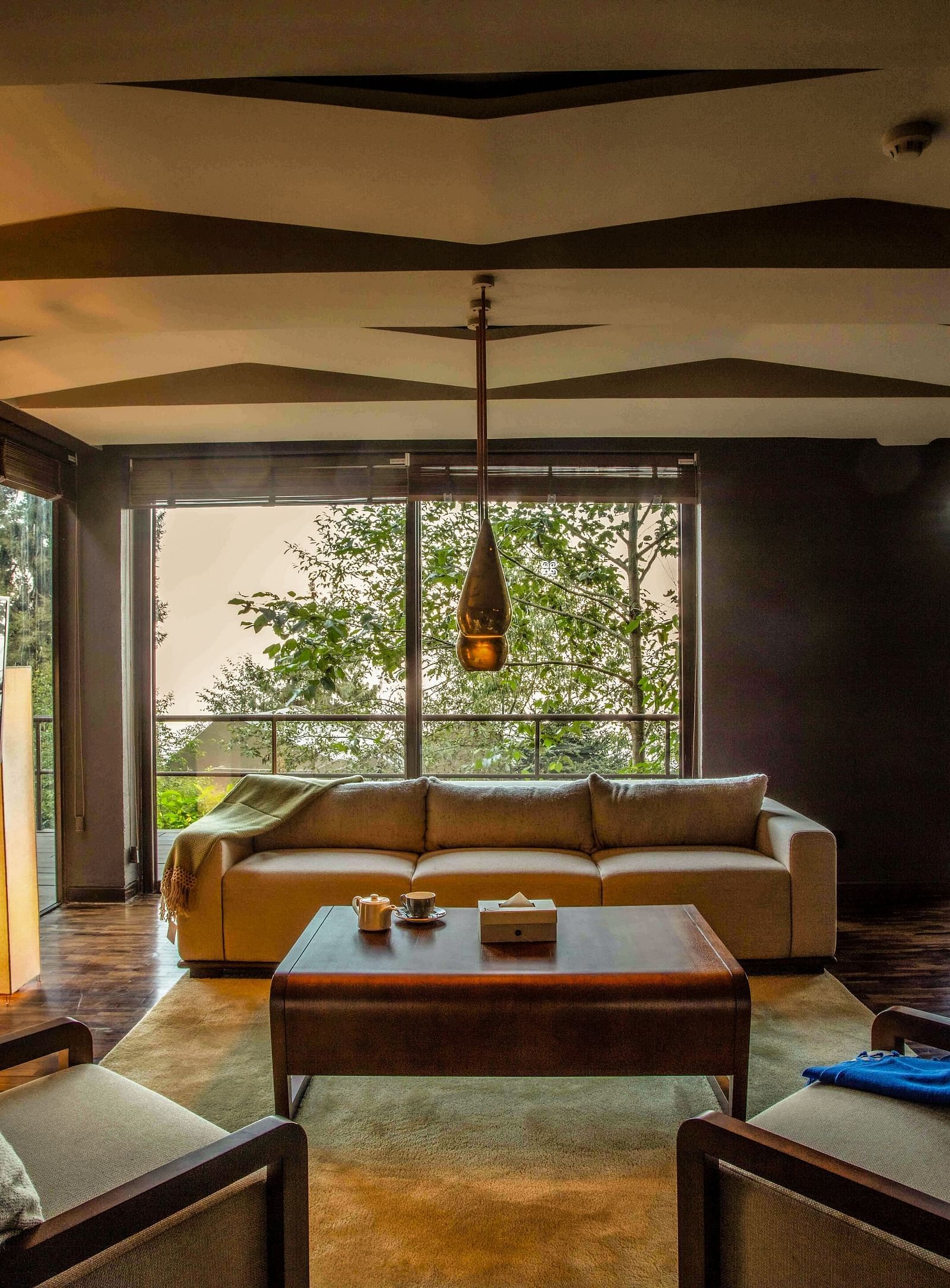 Spacious living room with modern decor, large windows offering a view of lush greenery.
