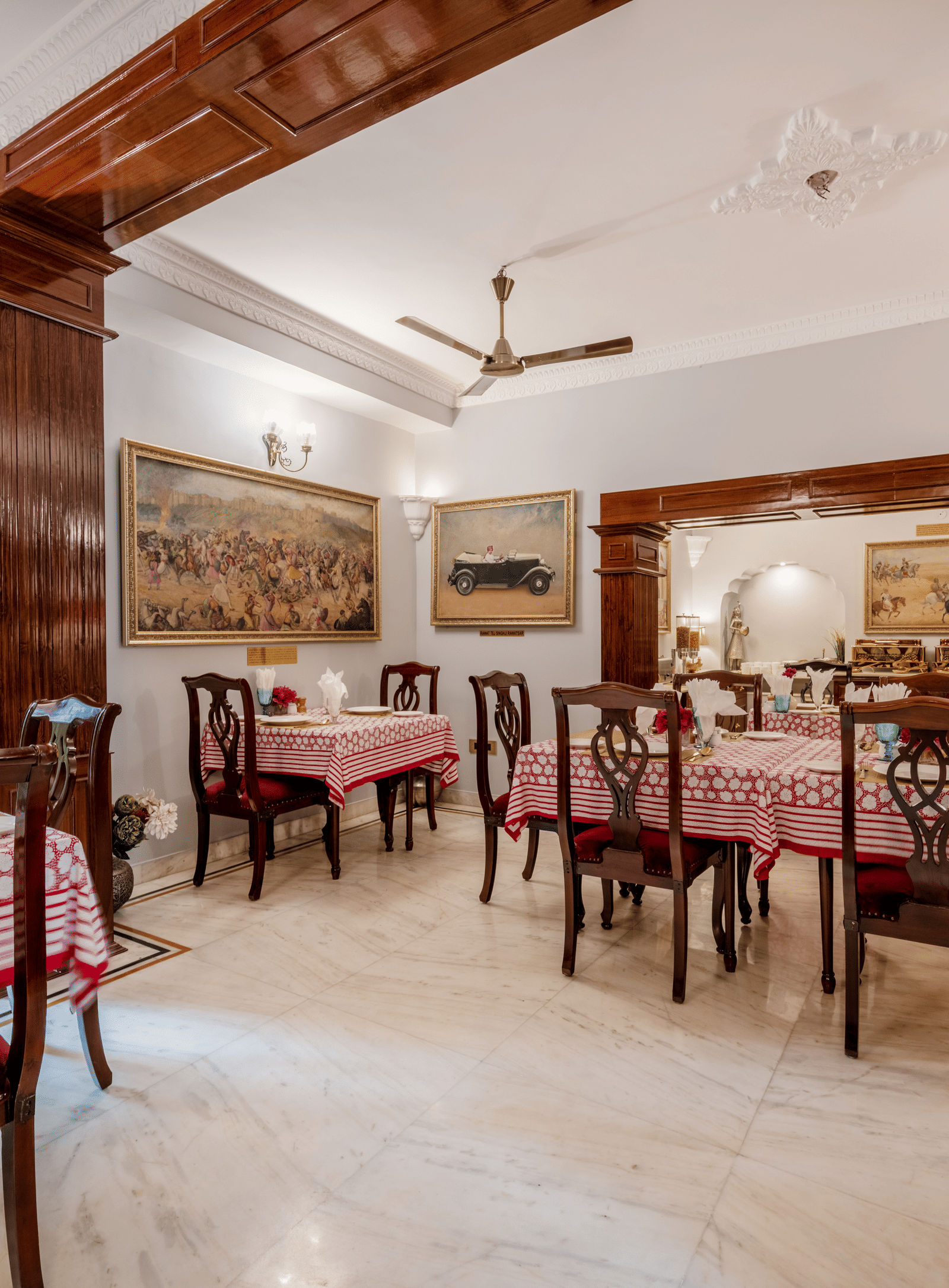 Spacious dining area with wooden chairs, tables, and ceiling fans under exposed beam ceiling at Dera Rawatsar, Jaipur.