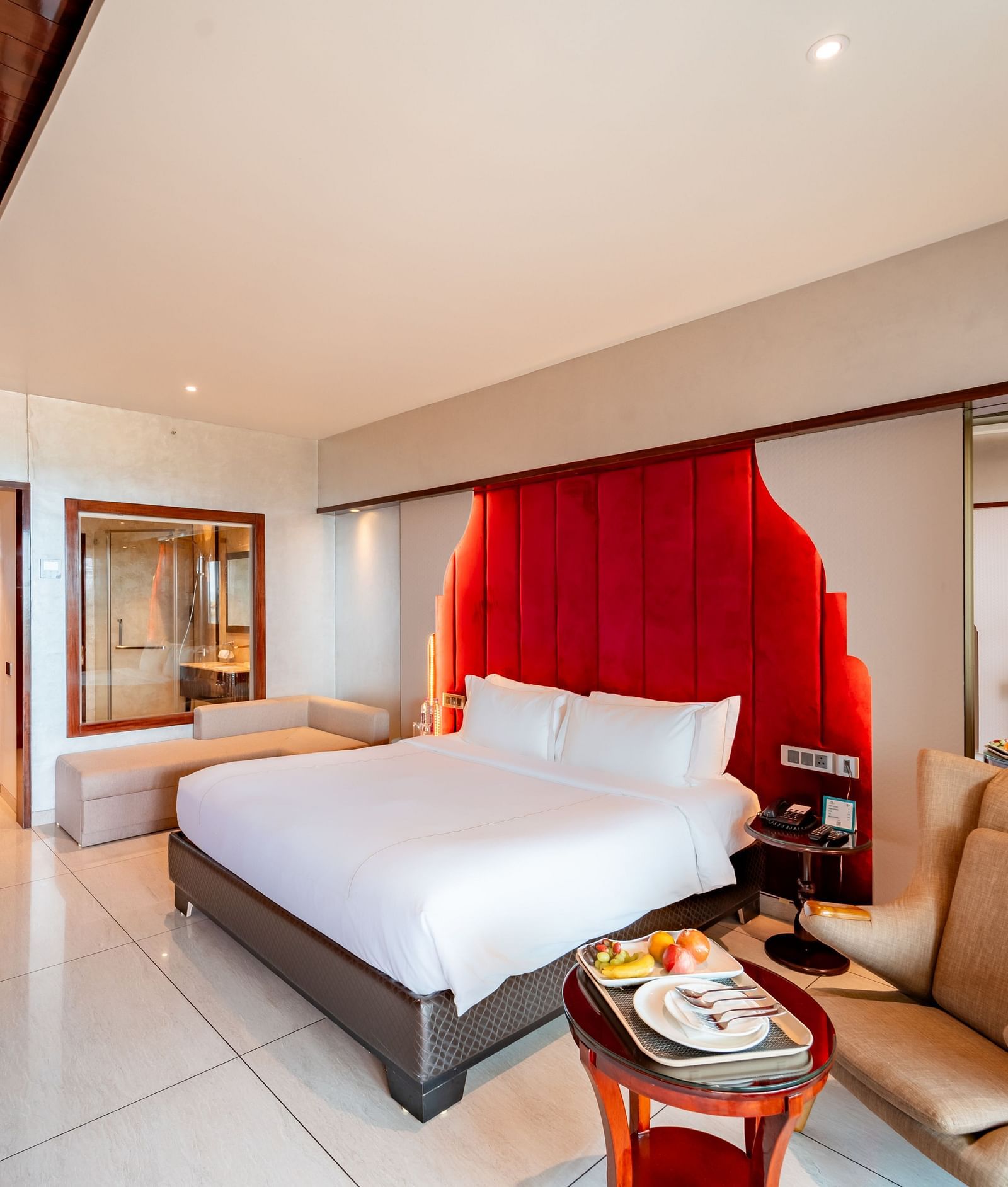 Executive Room features a spacious bed, a one-seater sofa with a round table and snacks, and a doorway leading to the exit at Crescent Spa & Resort, Indore.