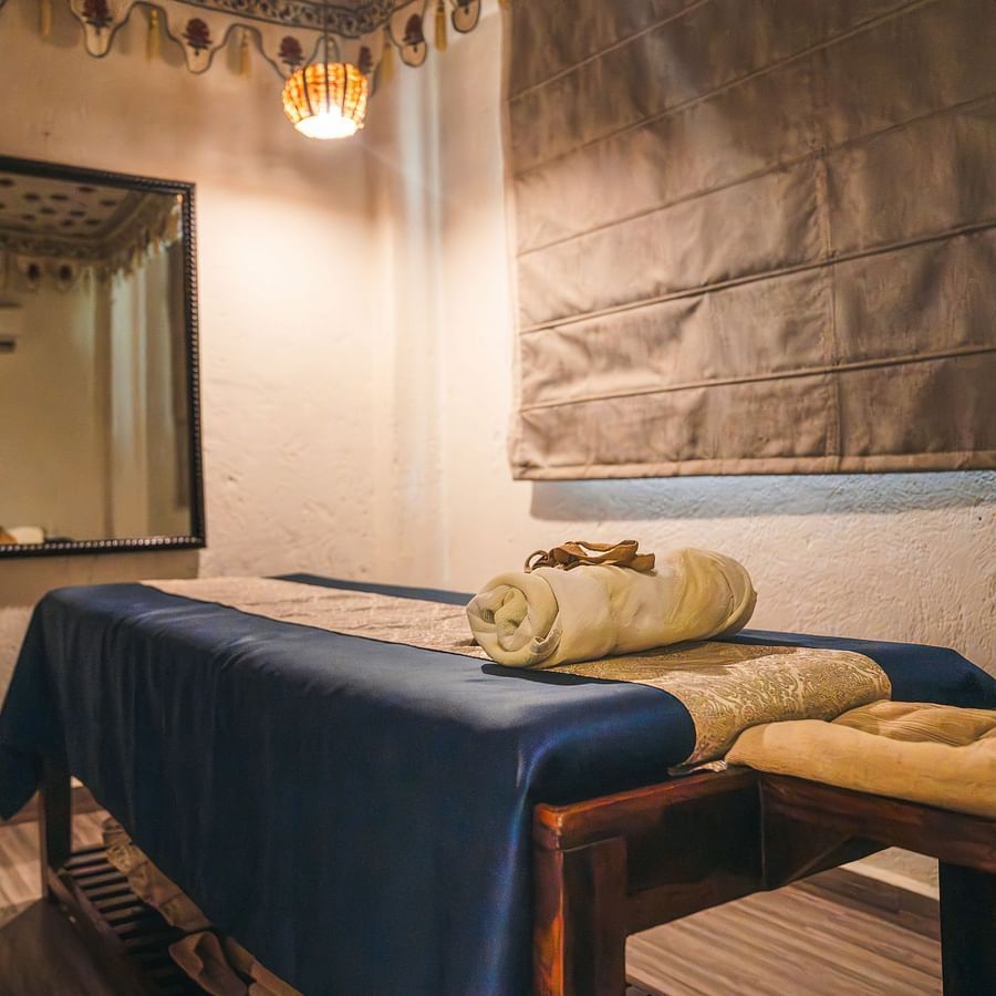 Spa table with a folded towel on top and a spa cloak hanging on the wall near a mirror.