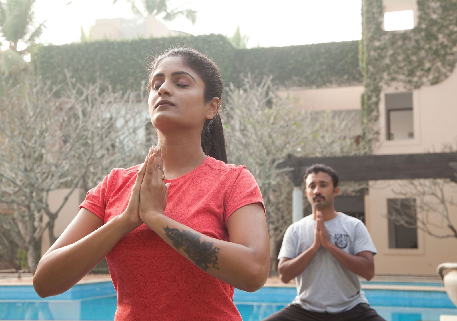 People doing yoga poses outdoors, sunlight, trees in background - Shreyas Retreat