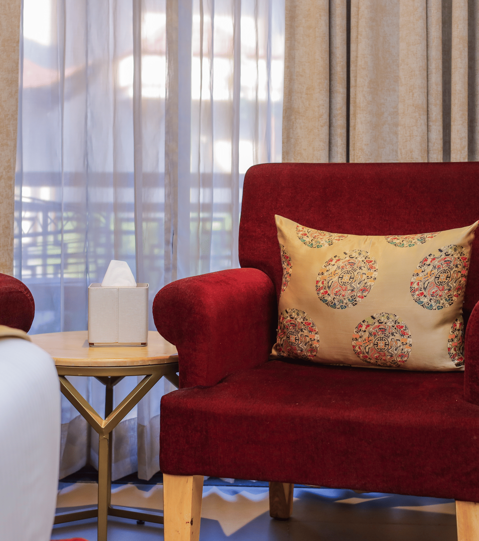 A pair of chairs with a small table placed near curtains inside a room at Ananta Spa & Resort, Jaipur.