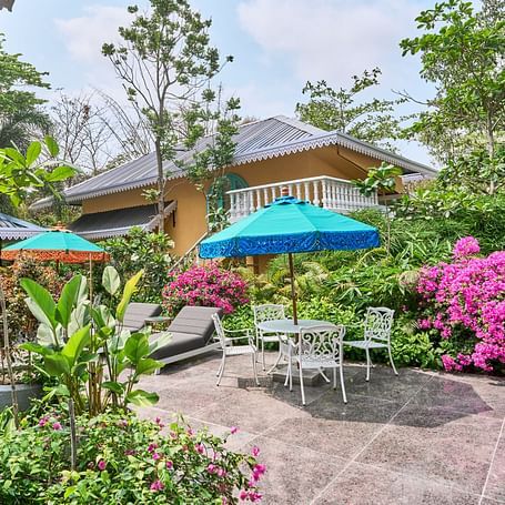 The exterior view of Mayfair Manor, Alibag, framed by trees and plants surrounding the property