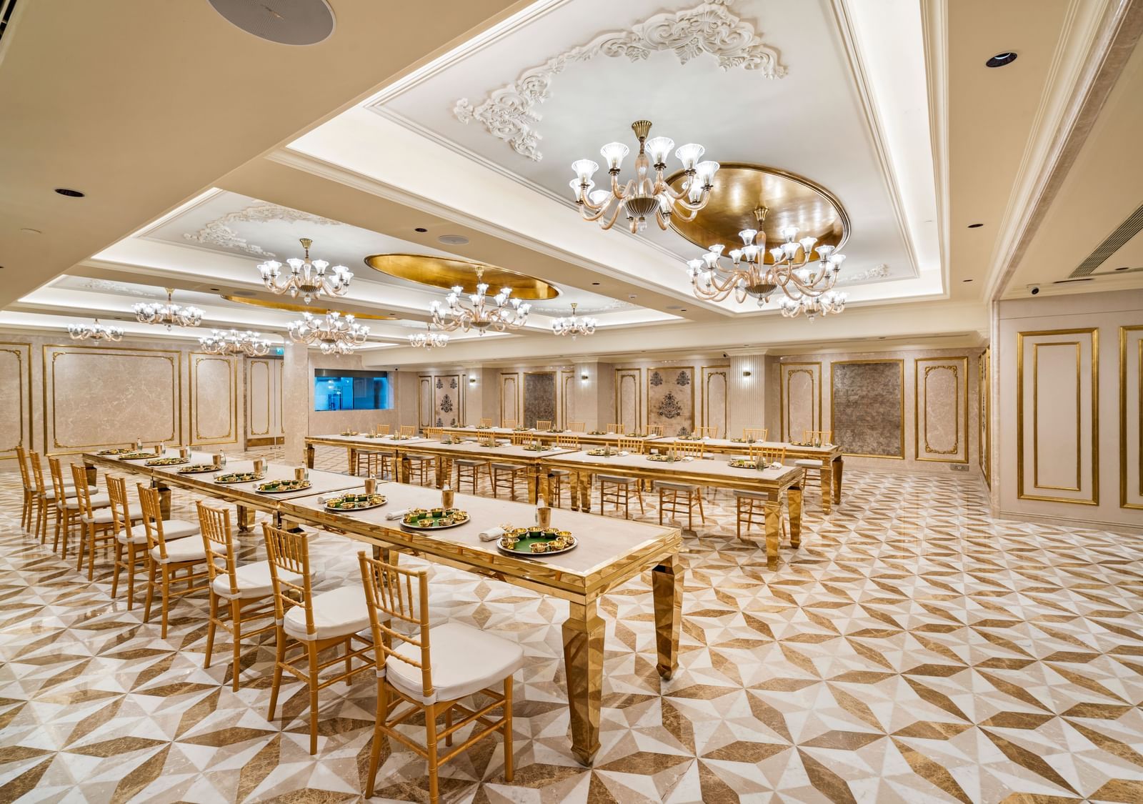 A spacious, well-lit banquet room with golden tables and chairs, set up for a large dining event at Grand Chennai by GRT Hotels