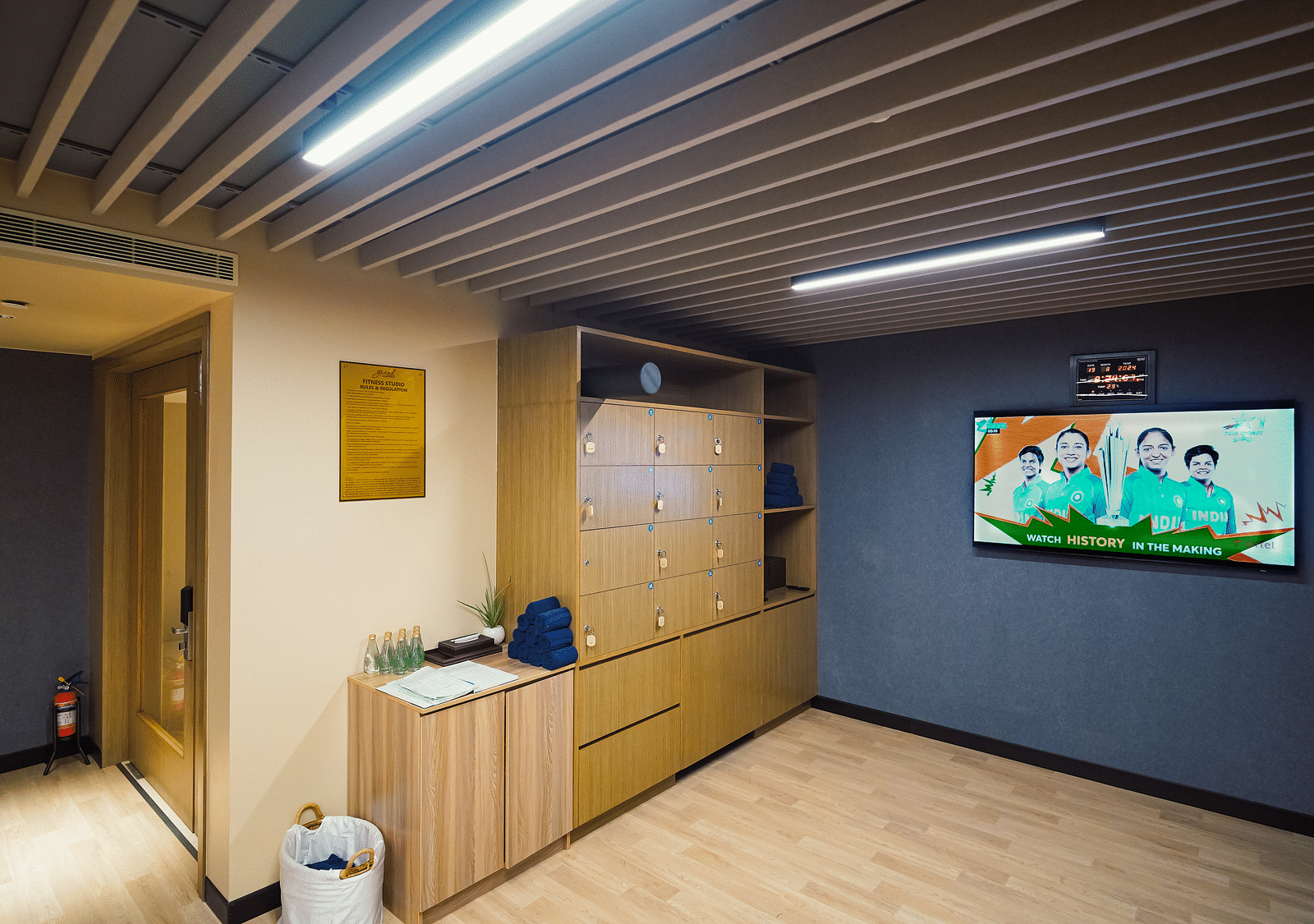 A tidy staff lounge with lockers, a TV, indoor plant, cabinet, bin, plaque, and fire extinguisher - Grand Madurai by GRT Hotels