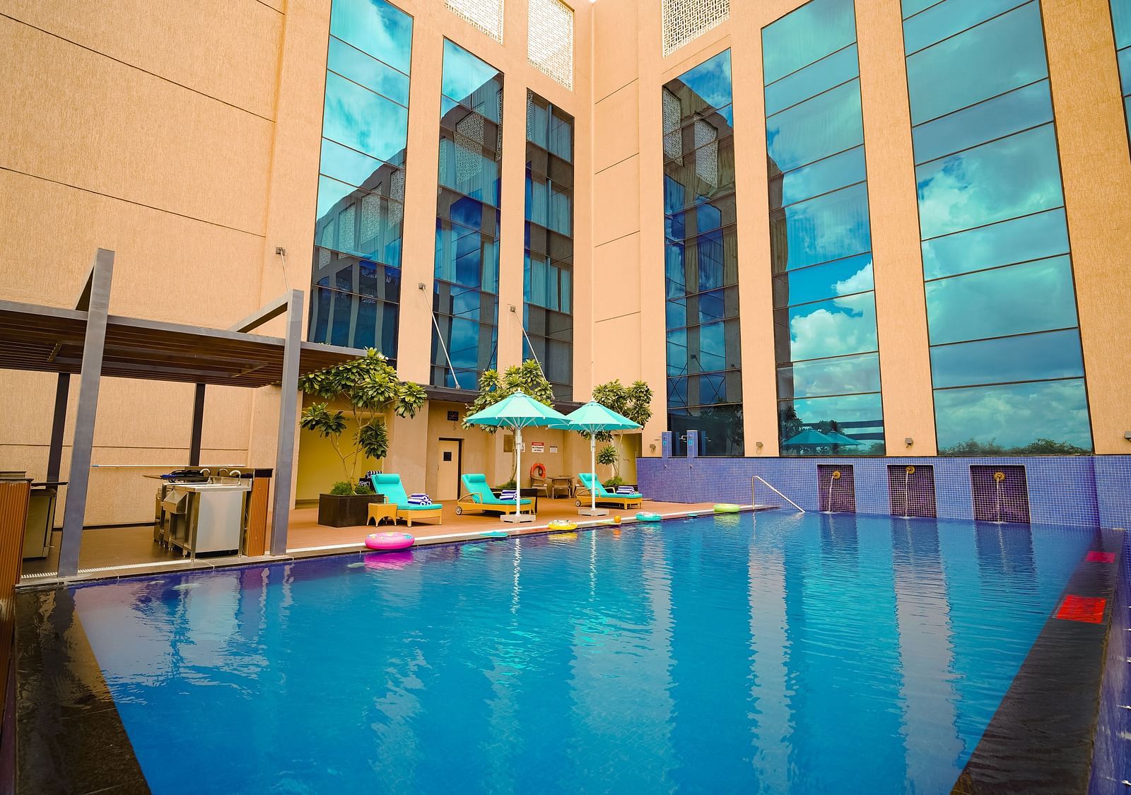A beautifully arranged poolside space with soft loungers and shady umbrellas, offering the perfect summer sanctuary - Grand Madurai by GRT Hotels