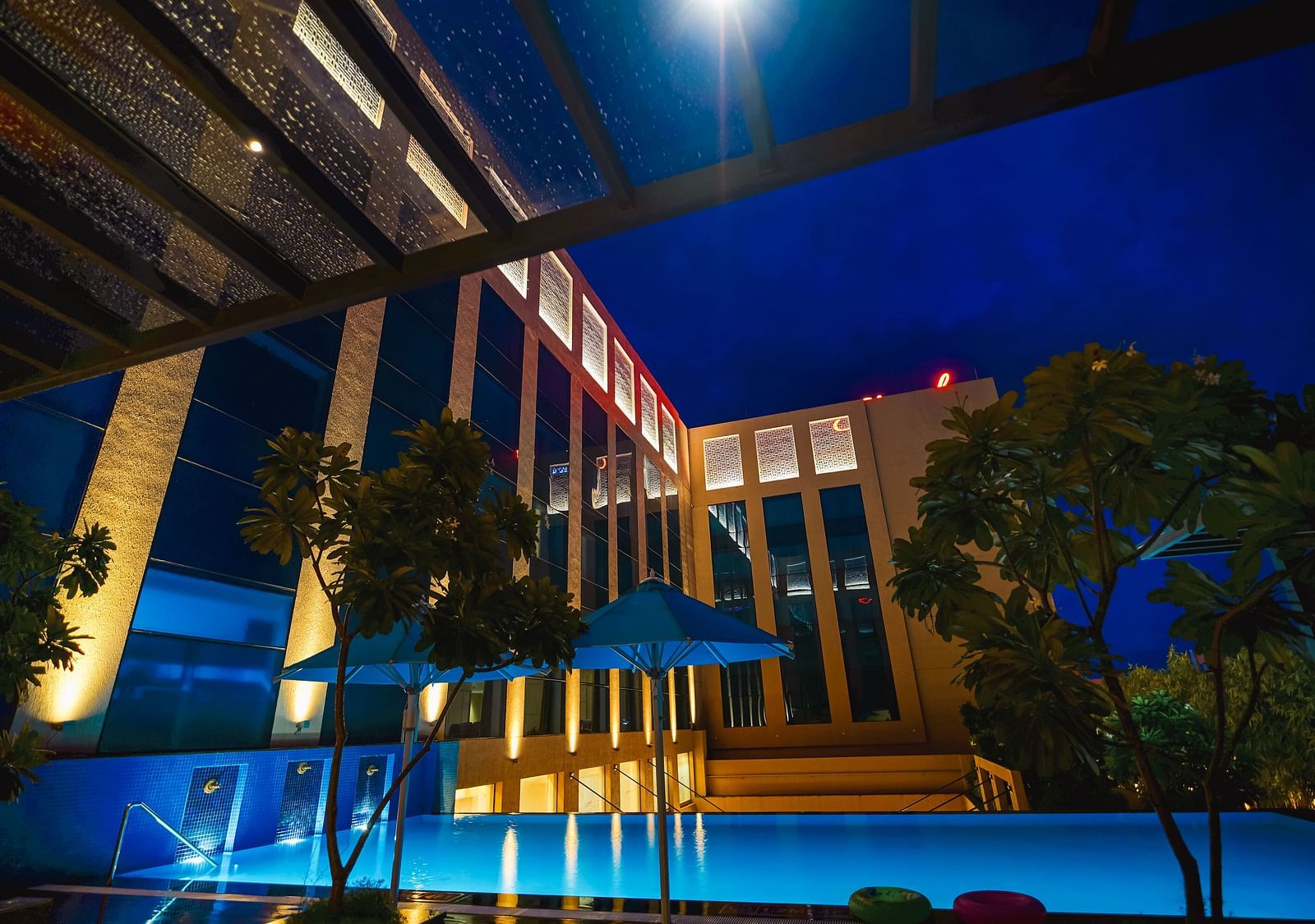 A stunning night shot of the pool area, beautifully lit, creating a magical evening ambience - Grand Madurai by GRT Hotels
