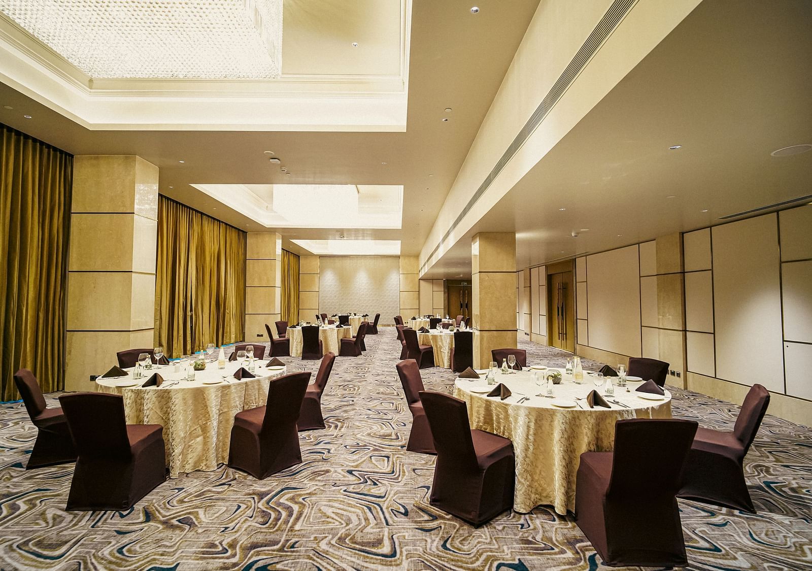 Our Banquet hall in Madurai with round tables, elegant chandeliers and warm lighting