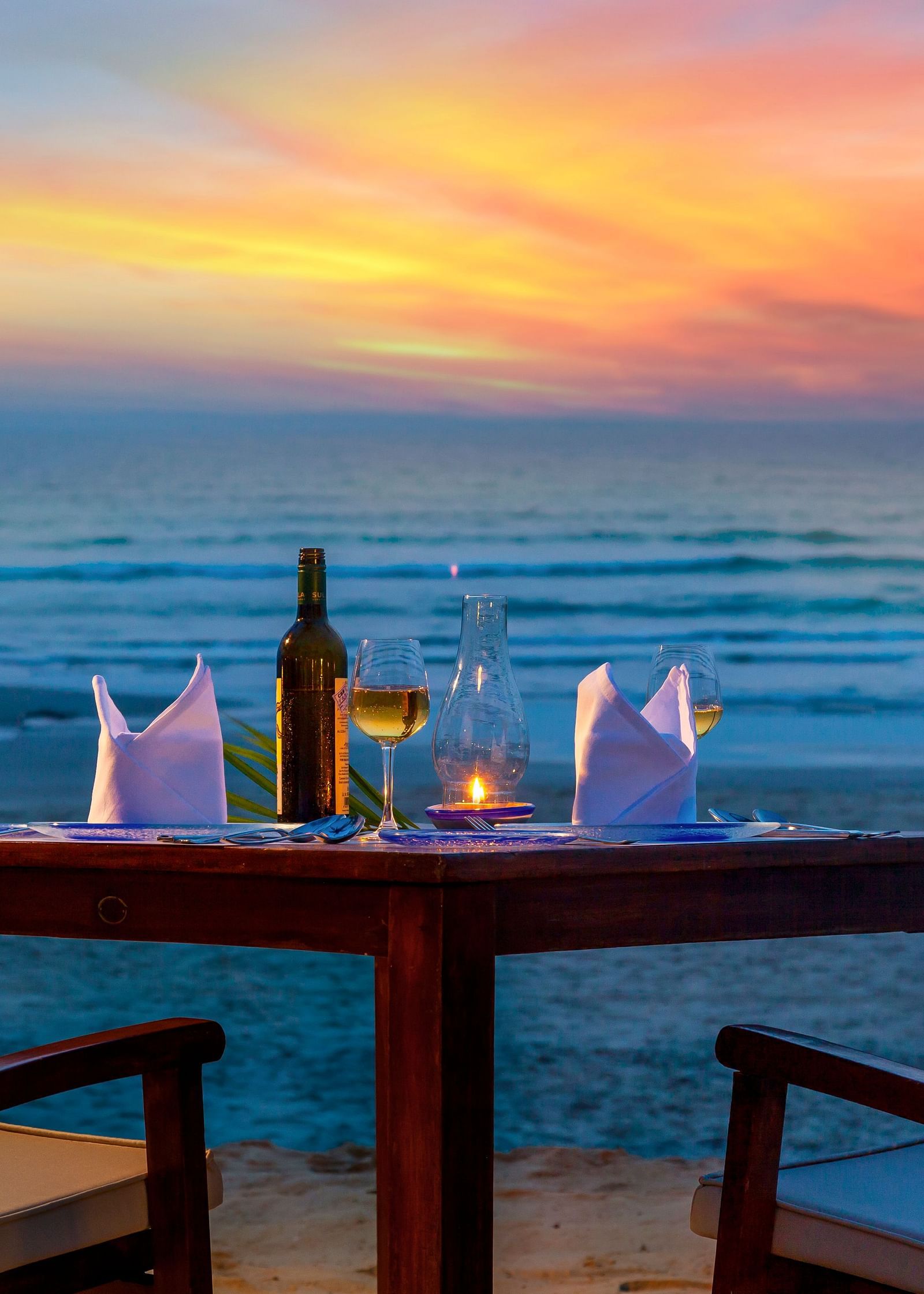 two chairs and a table set up near the beach - Private dining at Caravela Beach Resort Goa