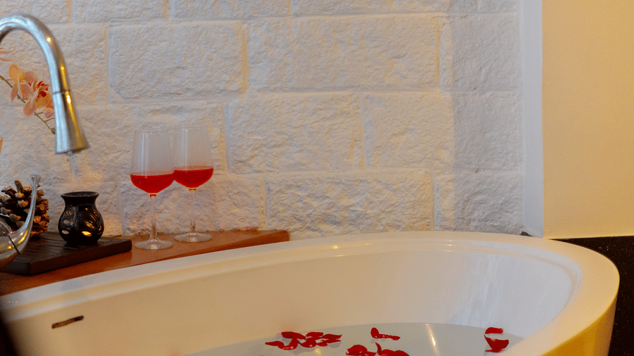 A luxury bathtub with rose petals, accompanied by glasses of wine for ultimate relaxation - Johnson Lodge & Spa, Manali