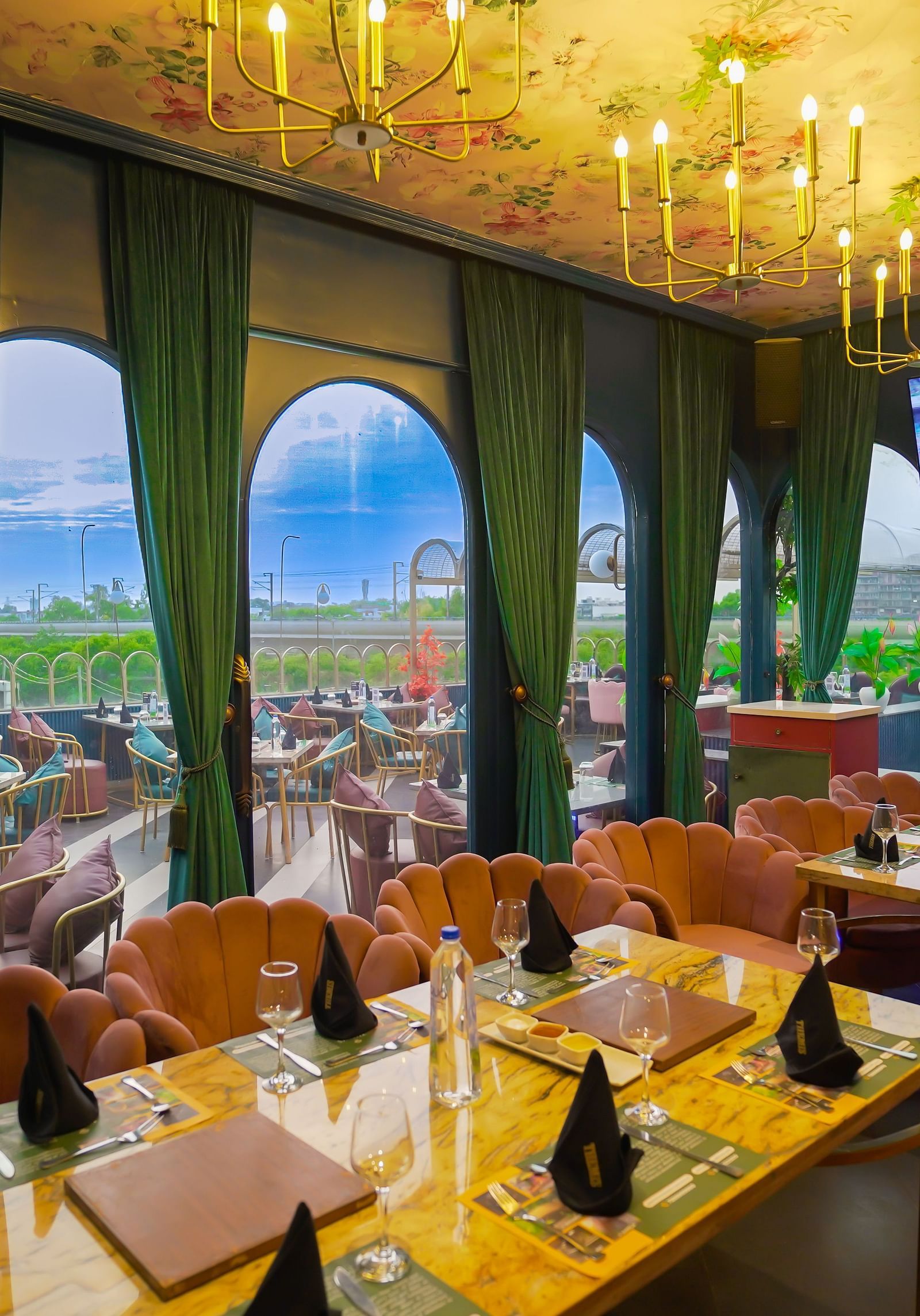 Dining tables at the restaurant with green curtains and candle light chandeliers Themis Barbecue House NSP Pitampura