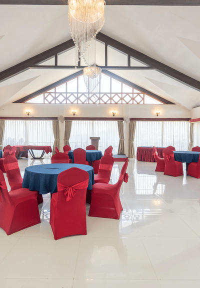 A shot of an expansive banquet hall with a seating arrangement featuring red and blue chairs and tables.