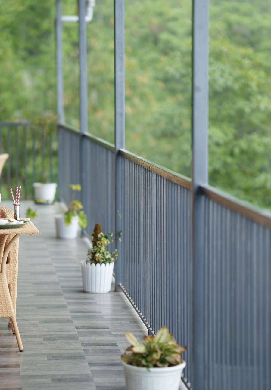  A view inside a hotel room at Summit Enigma Resort & Spa, Lamahatta, featuring a large bed, modern furnishings, and a window with a scenic outdoor view.