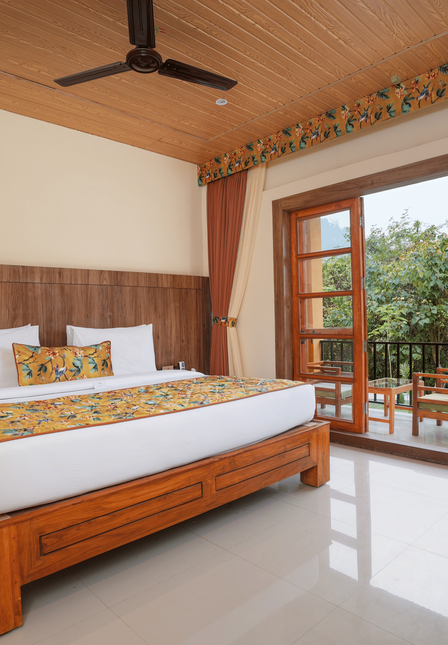 Bungalow featuring a spacious bed with wooden headboards, bedside table, and a large balcony at Summit Green Lake Tea Resort & Spa, Kaziranga