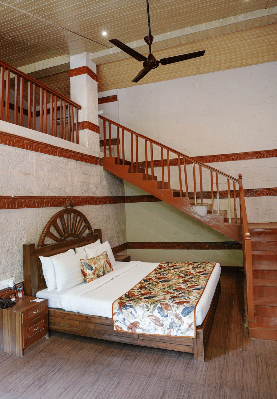 Duplex ethnic villa featuring a spacious bedroom and staircase leading to an additional room at Summit Green Lake Tea Resort & Spa, Kaziranga