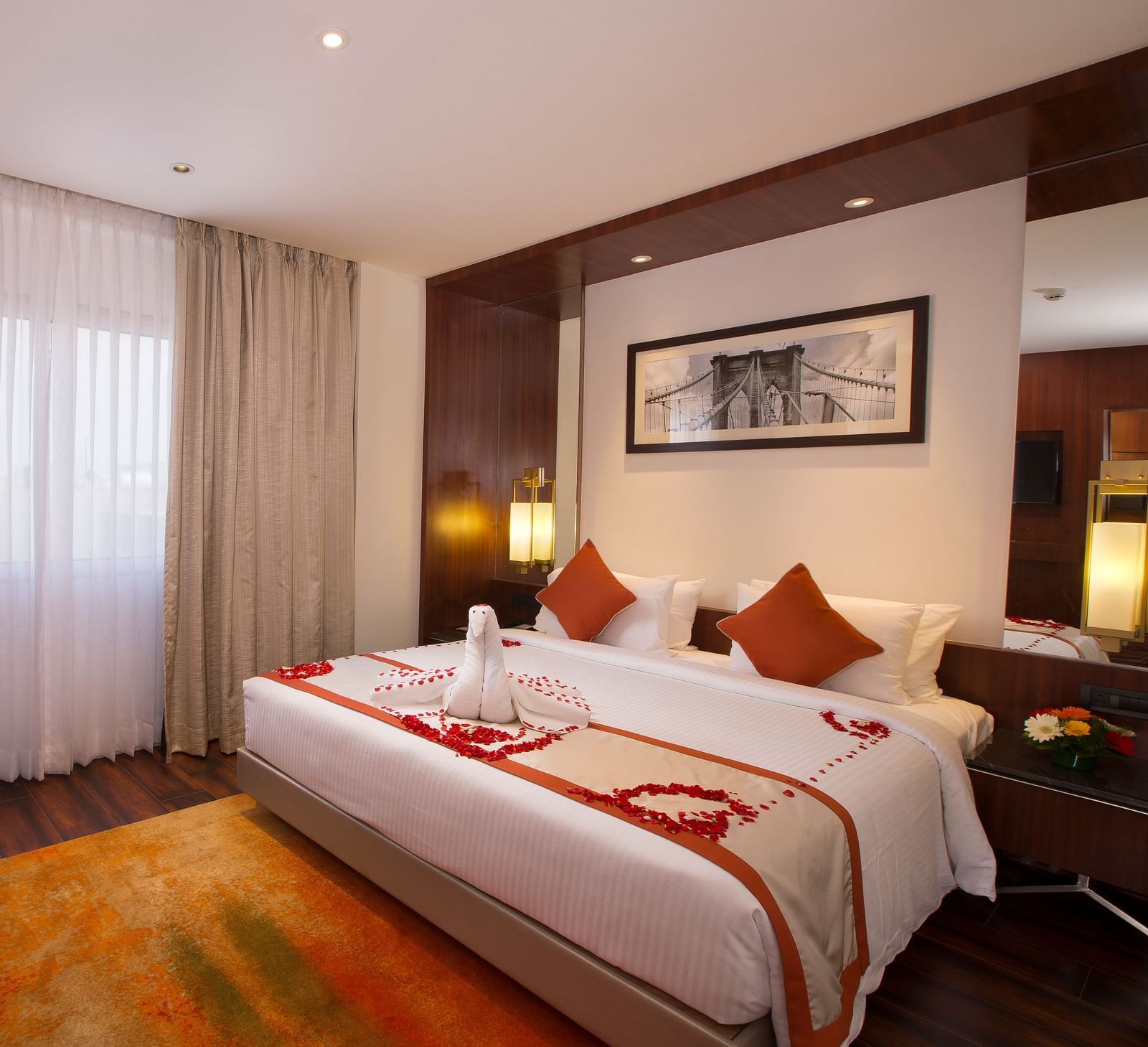 A hotel room with a large bed with white and orange linens, a brown office chair and sheer curtains over a window - Hotel Southend by TGI - Bommasandra, Bangalore