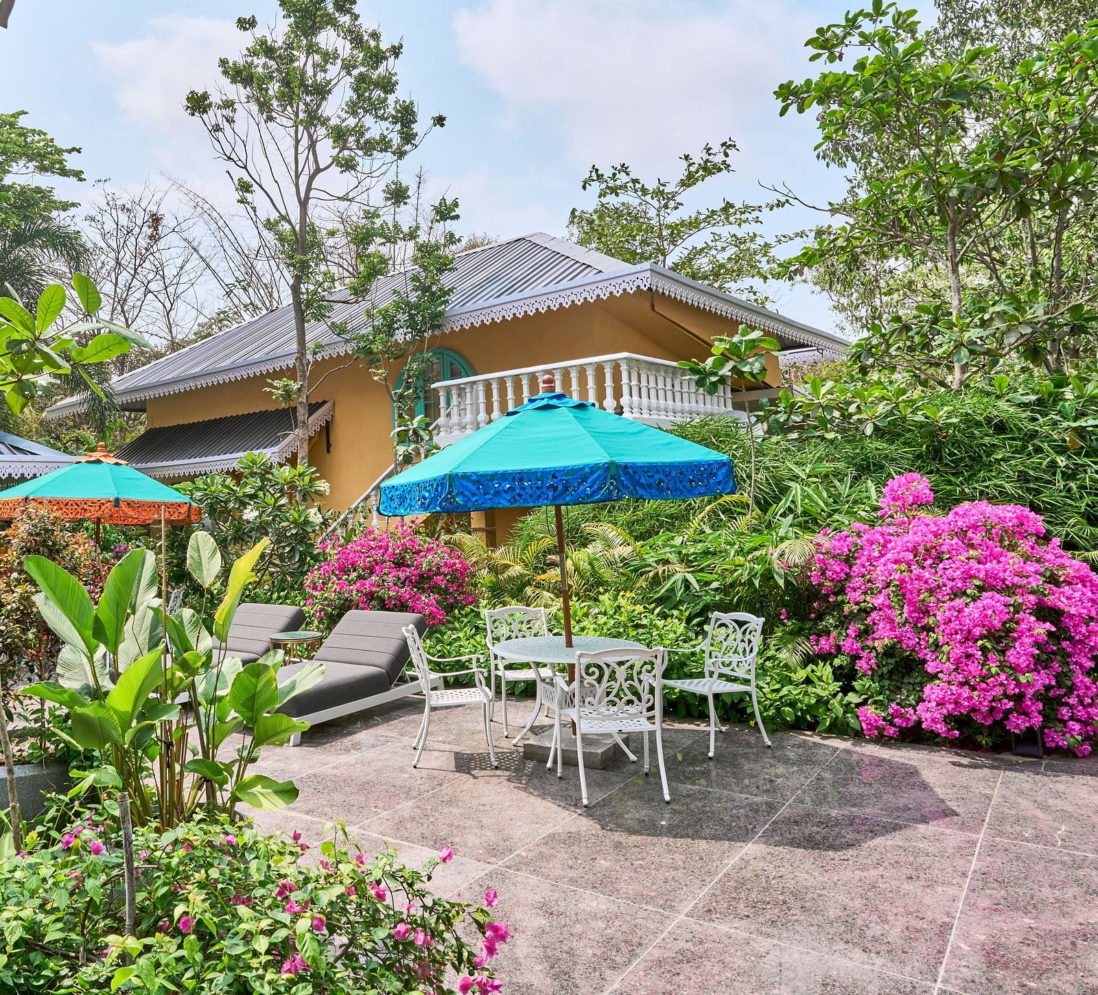 The exterior view of Mayfair Manor, Alibag, framed by trees and plants surrounding the property