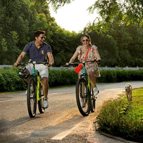 a couple cycling on a cycling track with garden on either side - Heritage Village Resorts & Spa, Manesar