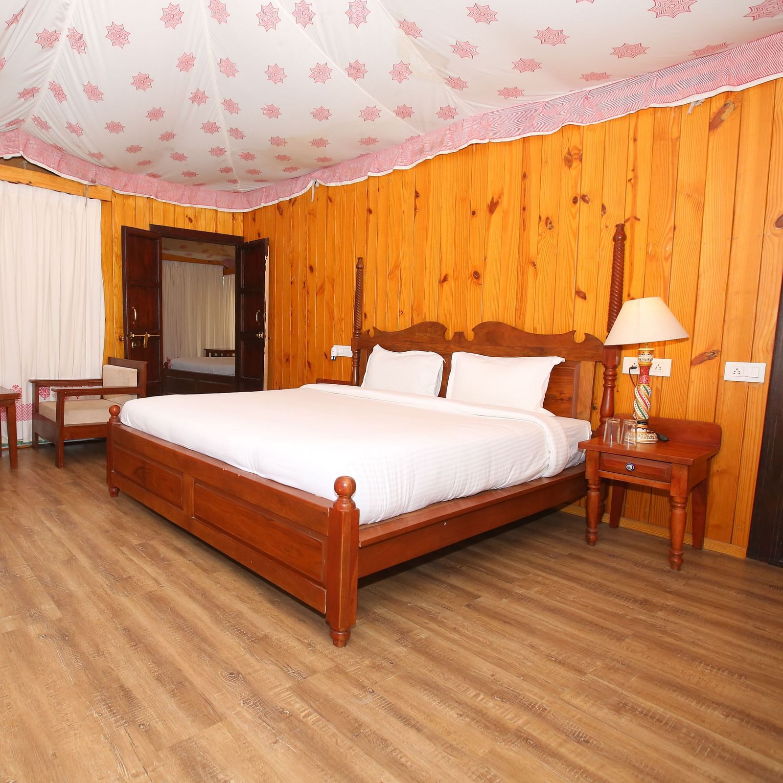 Luxury Wooden Tent featuring a king-sized bed, comfortable chairs, and stools at Aanandam Resort & Spa