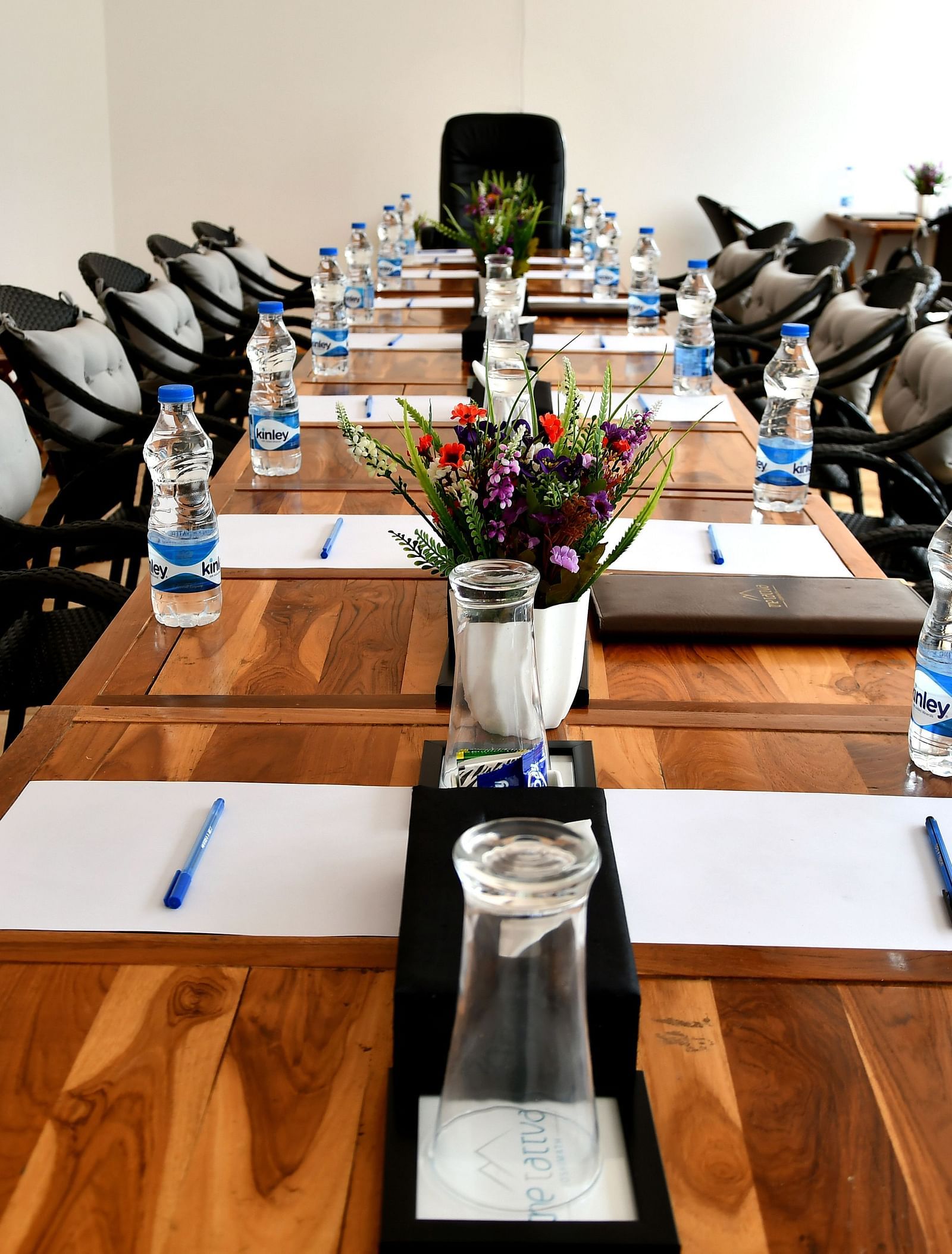 front view image of the conference hall featuring the expansive table decorated with flowers and stationery at the tattva, joshimath