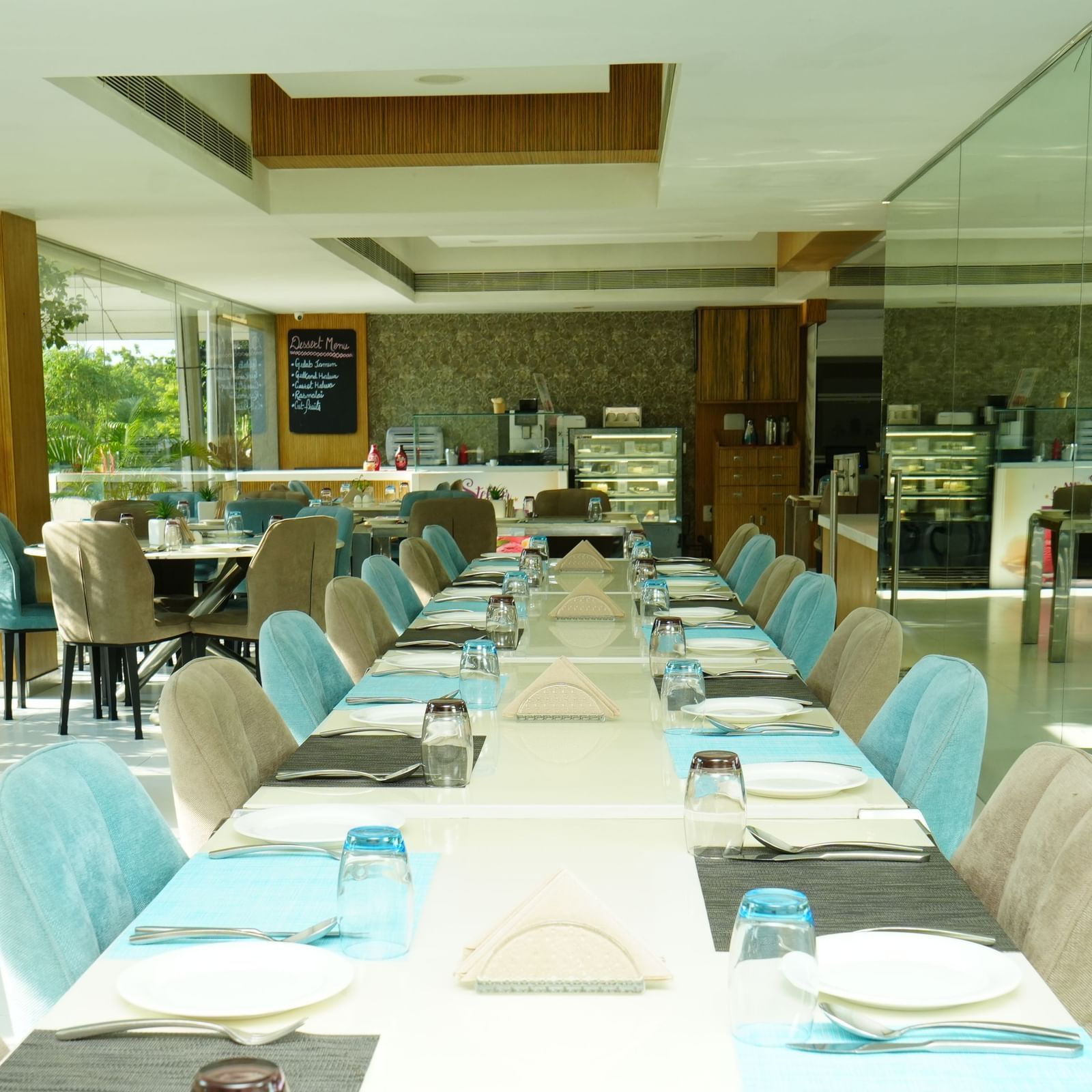 Long dining tables with blue chairs set inside a well-lit restaurant.Long dining tables with blue chairs set inside a well-lit restaurant at  Grande Bay Resort & Spa.
