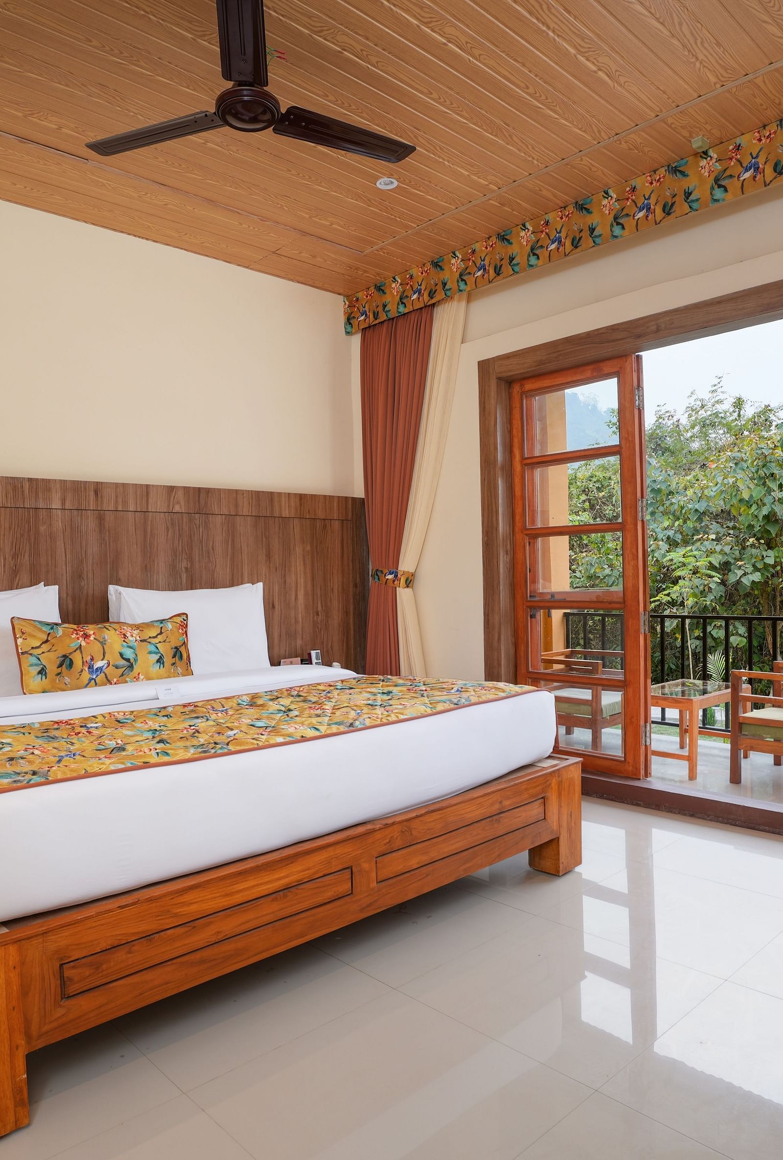 Bungalow featuring a spacious bed with wooden headboards, bedside table, and a large balcony at Summit Green Lake Tea Resort & Spa, Kaziranga