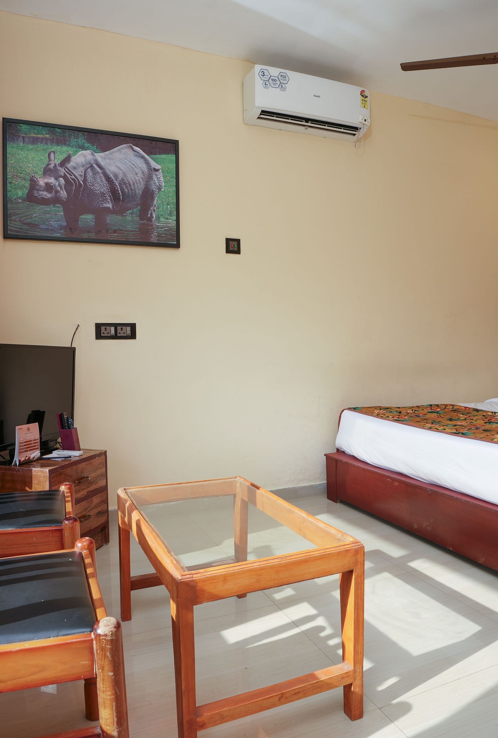 Deluxe Cottage featuring a spacious bed, television, air conditioner, glass table, and chairs at Summit Green Lake Tea Resort & Spa, Kaziranga