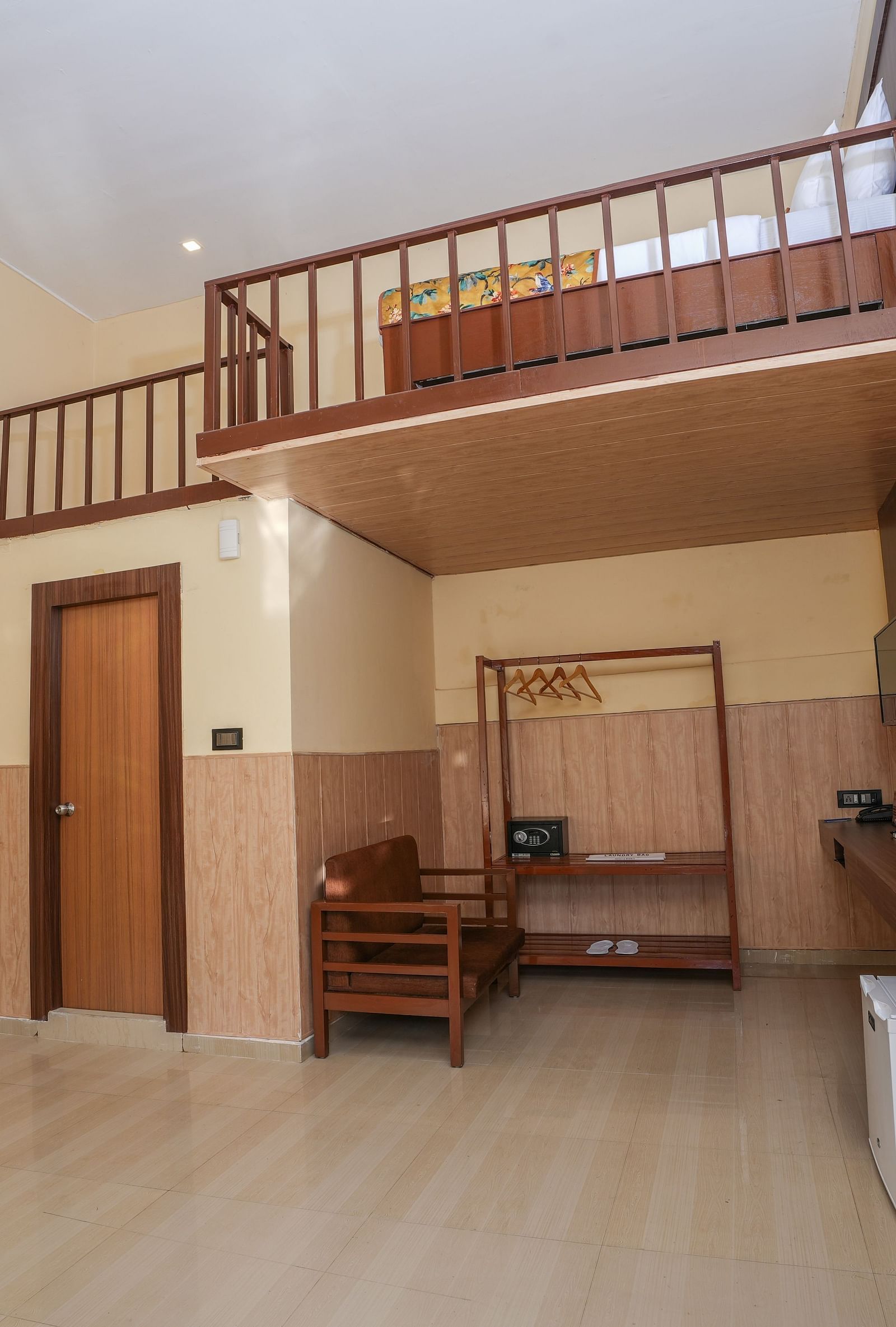 Duplex room with balcony features a living area with wooden furniture, a wine fridge, wall-mounted television, and stairs leading to the spacious bedroom at Summit Green Lake Tea Resort & Spa, Kaziranga
