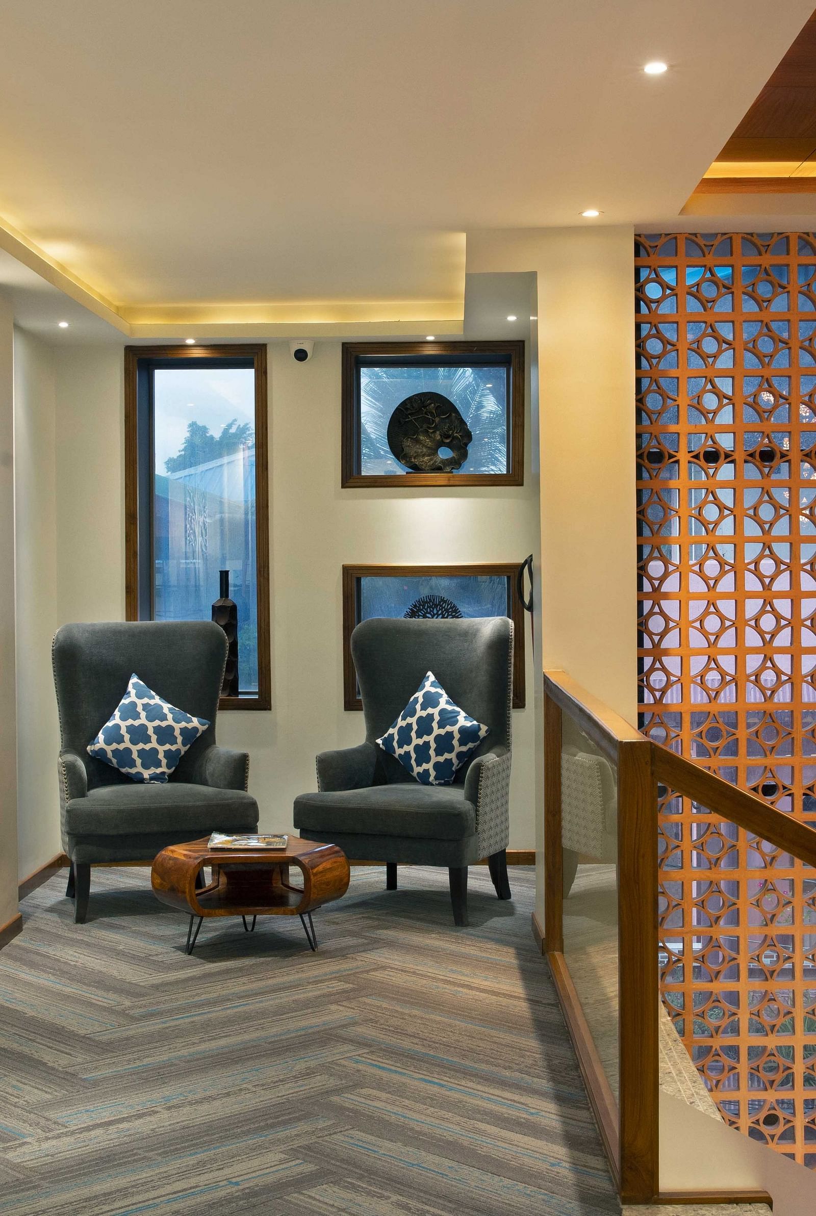 A lounge area at Coral Reef Hotel and Spa in Port Blair featuring two one seater couches placed next to each other and an ottoman on the floor