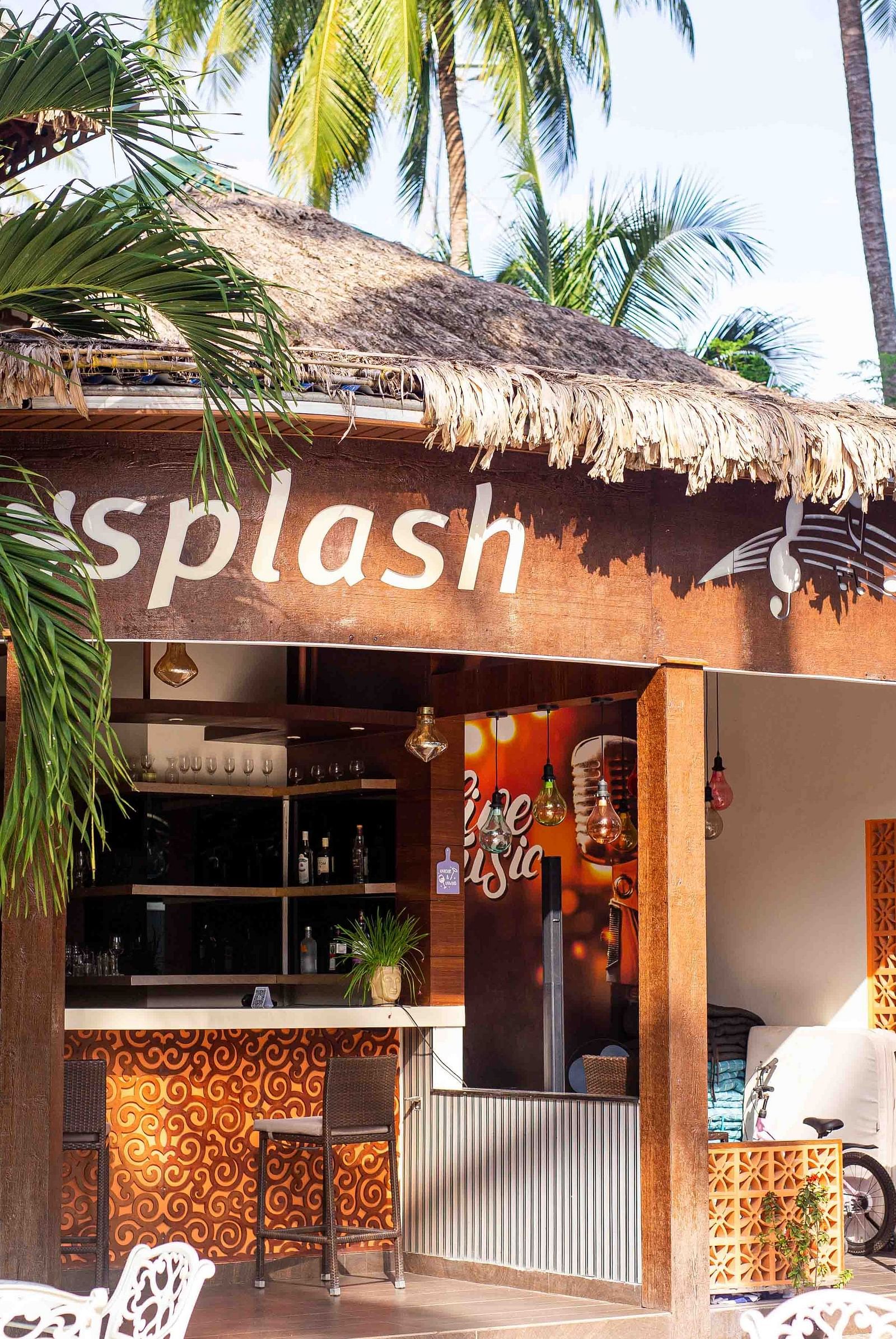 A small outdoor cafe named Splash, with a thatched roof and surrounded by tropical plants. The cafe provides a relaxed setting with outdoor seating - Coral Reef Resort & Spa, Havelock
