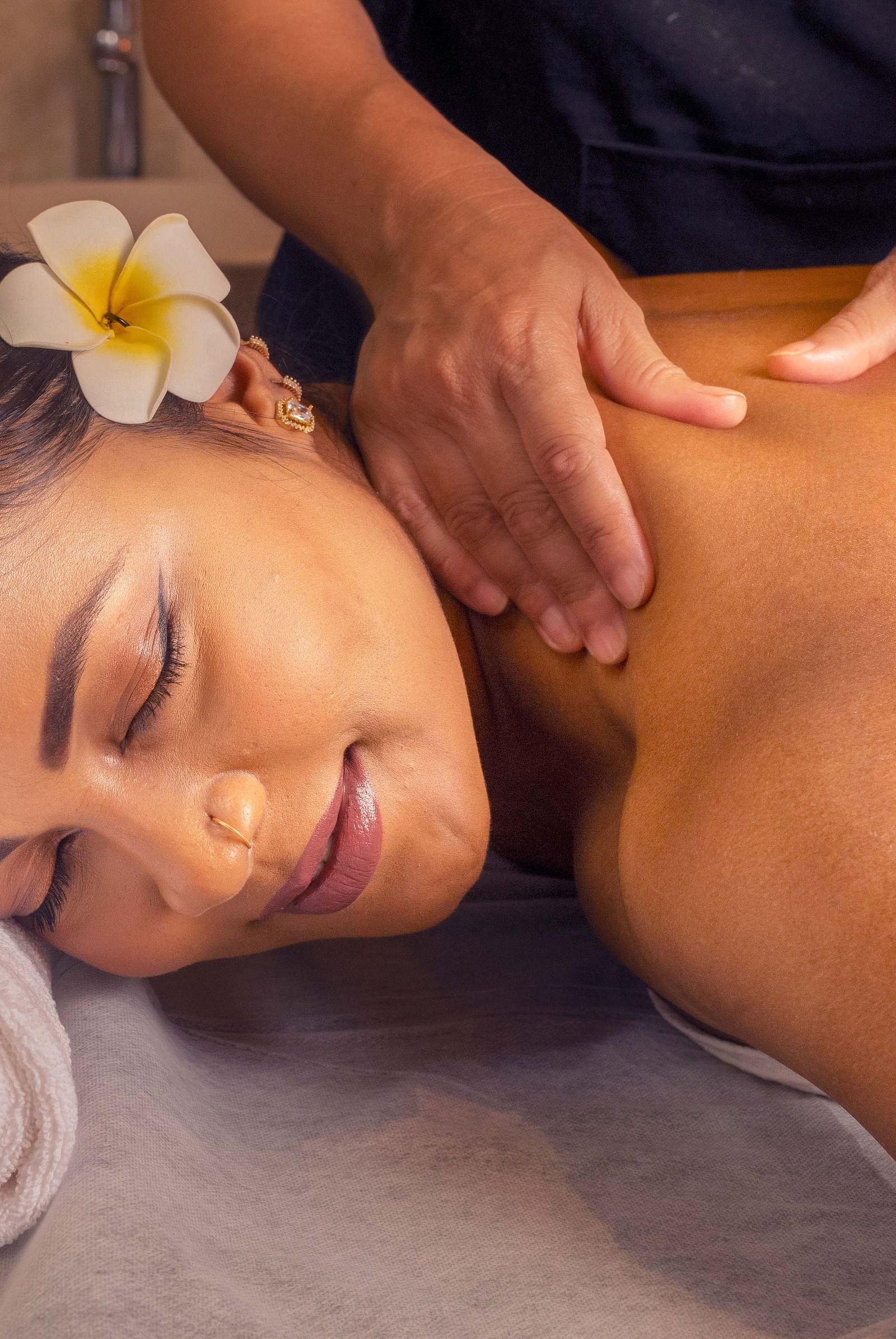  A woman receiving a soothing massage, surrounded by soft lighting and fresh flowers. The calm setting helps create a peaceful, spa-like experience - Coral Reef Resort & Spa, Havelock