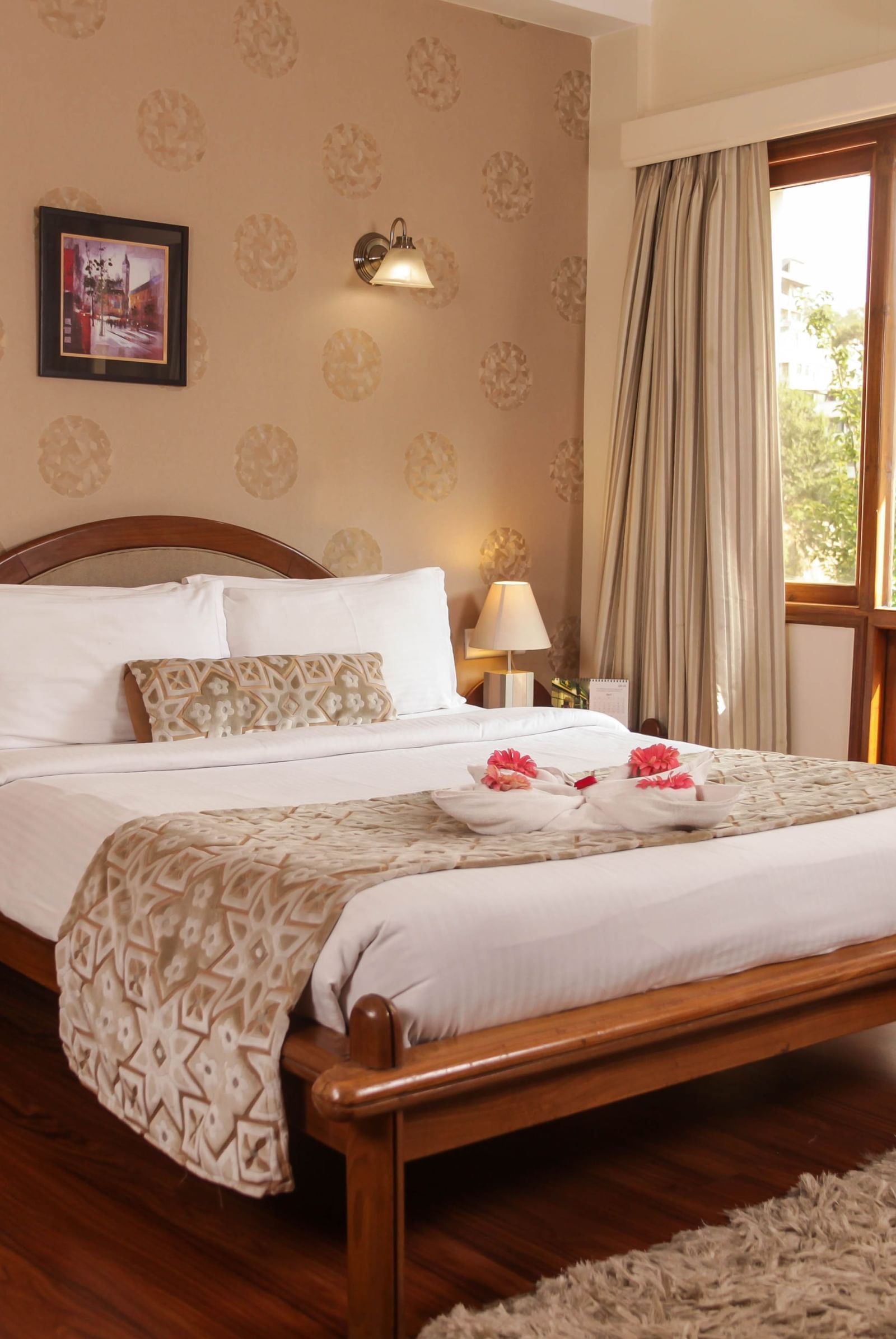 A well-lit bedroom at the Polo Hotel Shillong with a large bed, wooden floors, and a bright window.