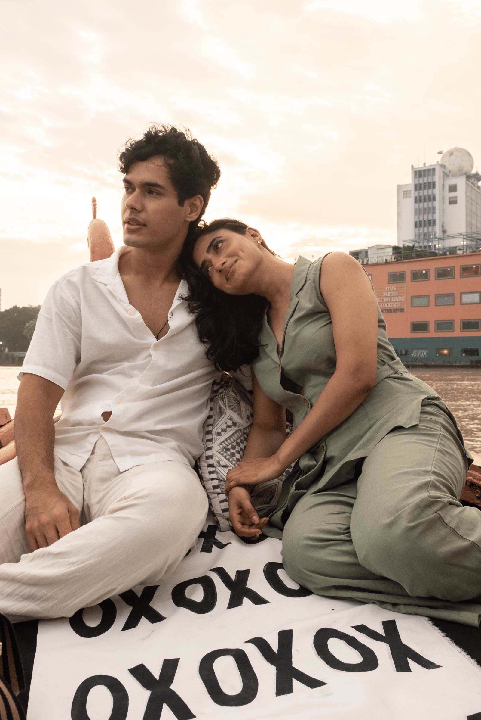 Couple sitting on a boat deck at Polo Floatel Kolkata with the river and cityscape in the background.