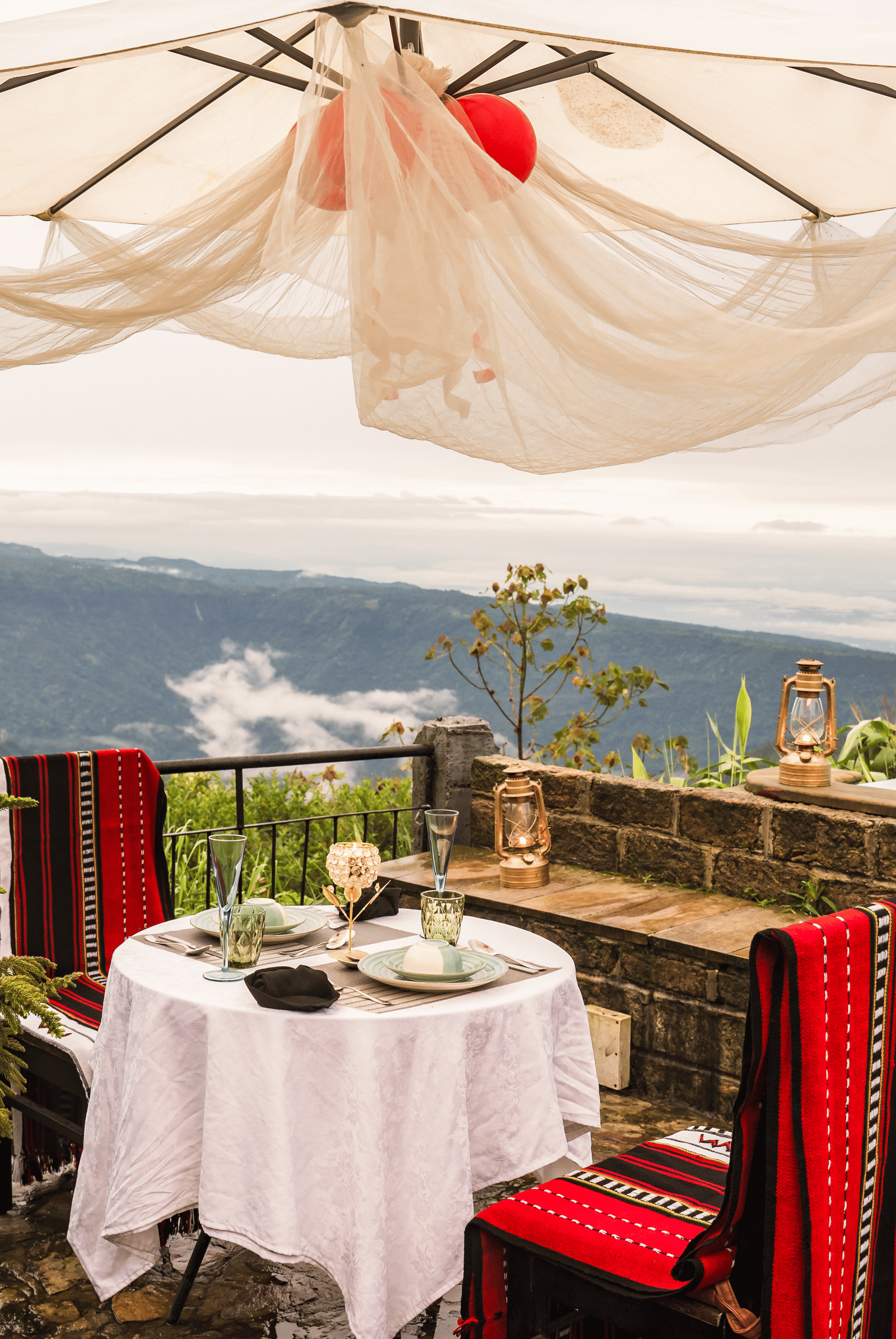 An outdoor dining area on a terrace at Polo Resort Cherrapunjee, overlooking a misty valley.